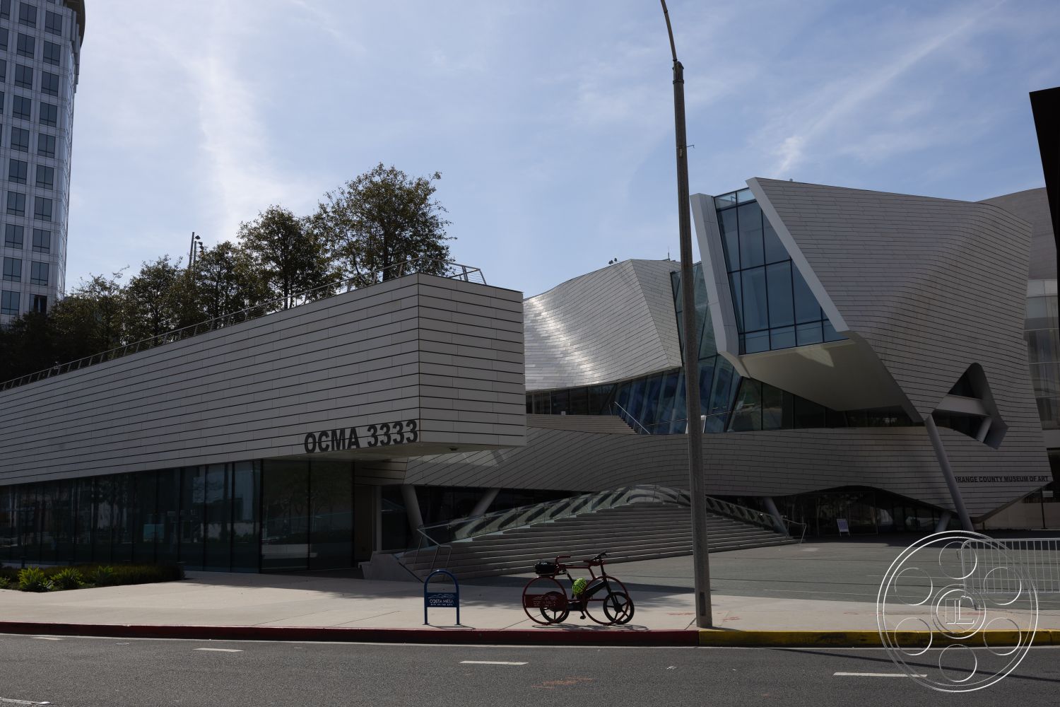 Museum 4 - exterior, urban setting, contemporary design elements, modern architectural style, tree-lined street, large overhangs, landscaped garden area, floor-to-ceiling glass windows, open-air plaza, steel frame construction, glass curtain wall, angular roof forms, textured metal siding, porous concrete walkway, sloped roof sections, curved building facade, street-level entrance, intersecting geometric shapes, public art display, masonry planters