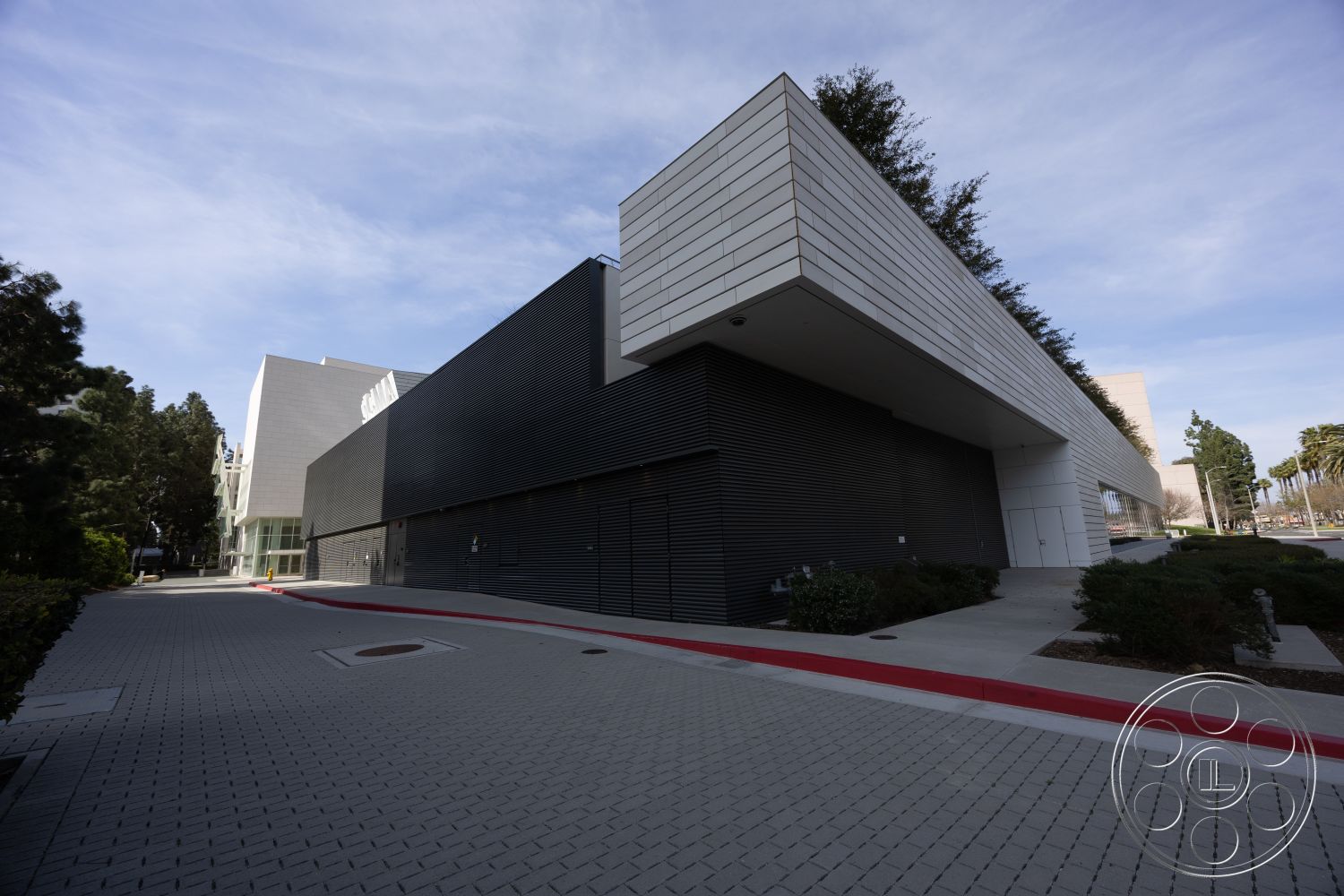 Museum 4 - exterior, large glass windows, urban setting, modern architectural style, landscaped green areas, red curb, concrete sidewalk, metal panel siding, black horizontal wood slats, asymmetrical building shape