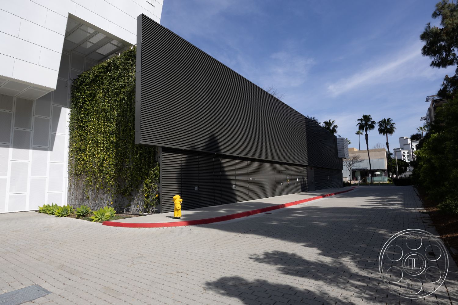 Museum 4 - exterior landscape with palm trees, exterior urban setting, exterior concrete pavers driveway, exterior black horizontal wood slatted wall, exterior living wall with greenery, exterior white stucco building facade, exterior red curb for parking, exterior linear architectural forms, exterior contemporary architectural style, exterior smooth surface textures, exterior irrigation-friendly landscaping