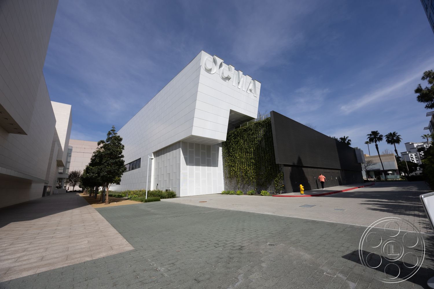 Museum 4 - exterior, modern architectural lines, outdoor seating area, urban setting, lush landscaping, landscape greenery, artistic wall treatments, pedestrian walkway, black wood paneling, floor-to-ceiling glass windows, commercial building design, textured concrete façade, white stone cladding, paver stone pathway, inclusive public space, natural light utilization, contemporary design features