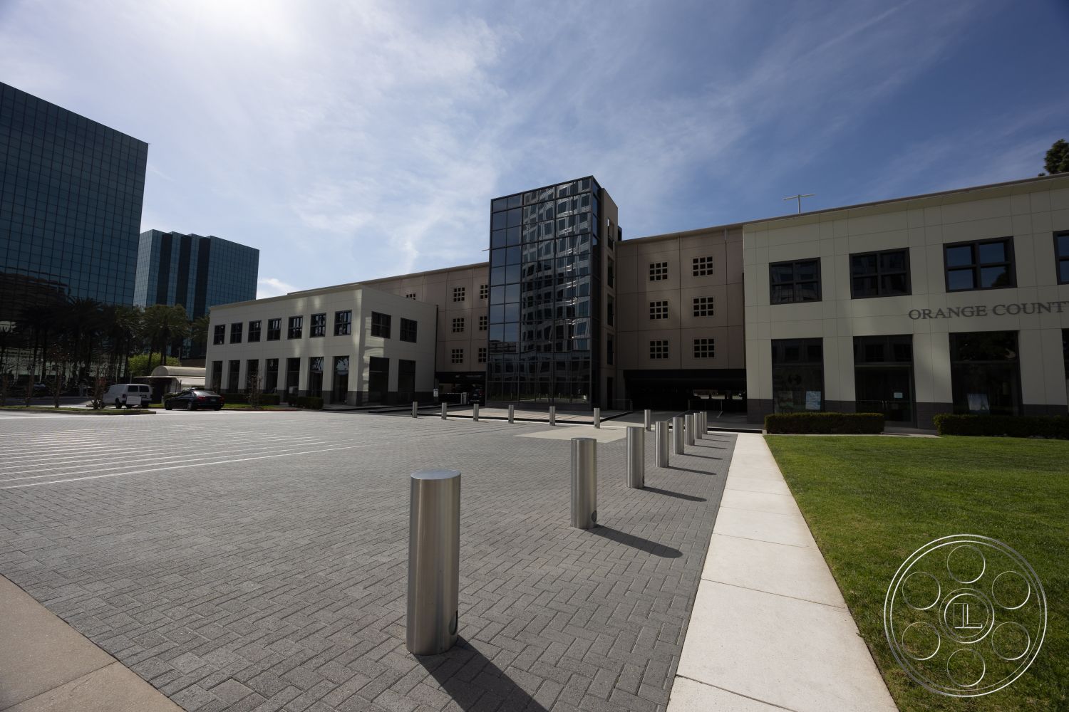 Museum 4 - large windows, exterior, modern architectural style, cityscape background, glass curtain wall facade, two-story office building, commercial building setting, grey concrete pavers driveway, steel bollards, white stucco building exterior, green grass landscaping, urban office complex, rectangular plaza layout, open air public space