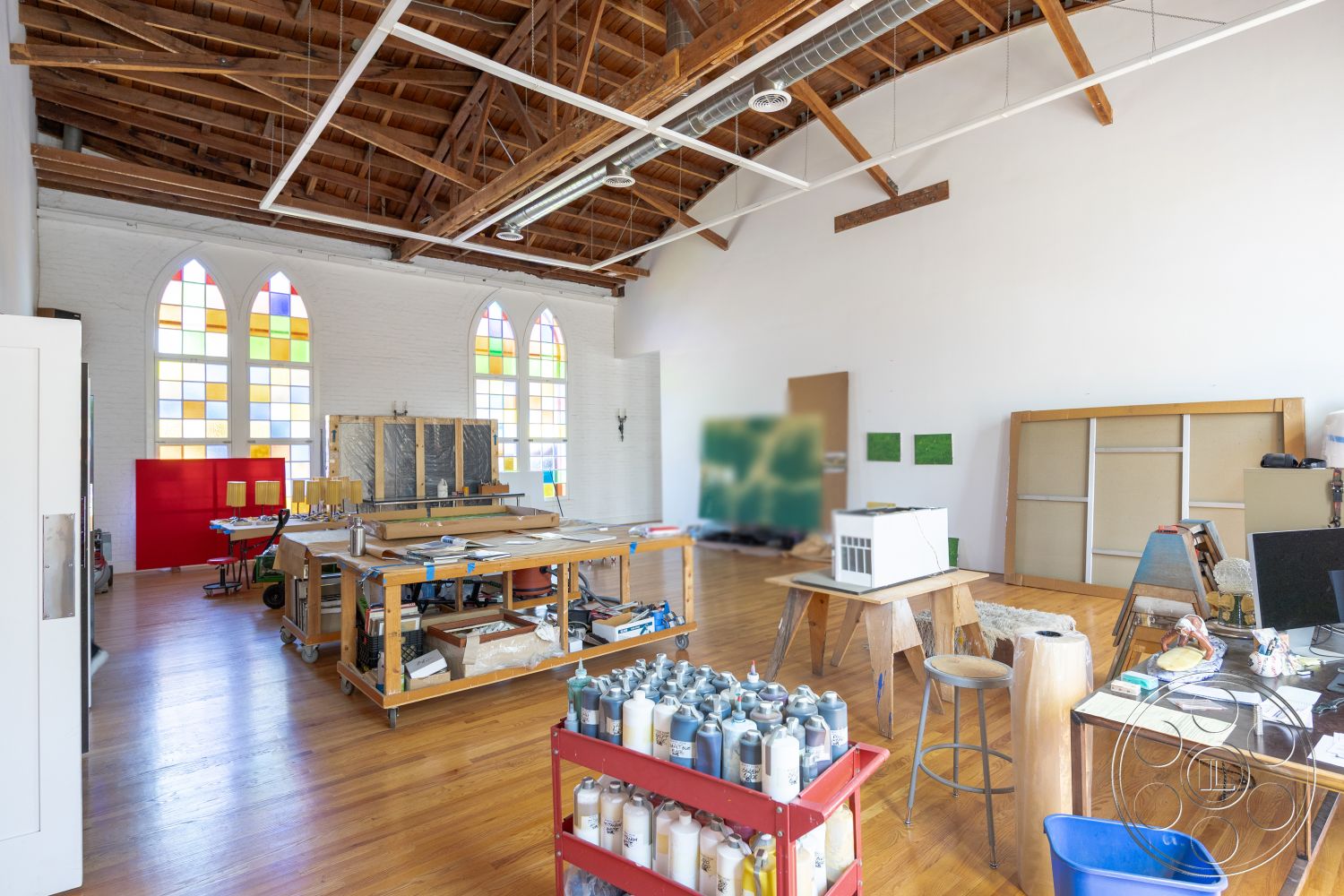 Studio 100 - large windows, natural light, functional layout, minimalist design elements, artistic workspace, creative environment, eclectic furnishings, white painted walls, exposed wood beam ceiling, bright interior lighting, open workspace design, urban art space, hardwood studio floor, arched stained glass windows, wooden work tables, colorful art studio decor, contemporary art studio