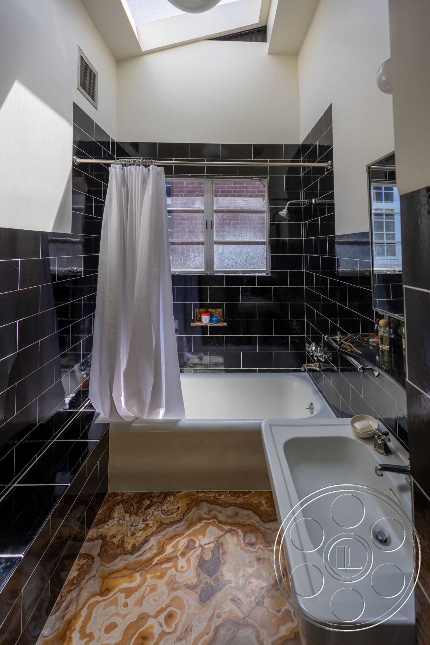 Studio 100 - white porcelain sink, interior bathroom, modern bathroom design, skylight ceiling, black glazed tile bathroom walls, rectangular bathtub, textured marble bathroom flooring, chrome bathroom fixtures, white fabric shower curtain