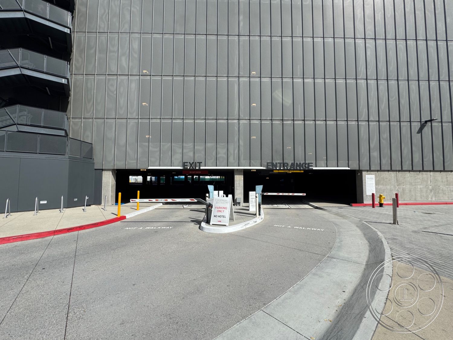 Office 121 - exposed concrete walls, asphalt driveway, steel frame structure, glass curtain wall, industrial architectural style, commercial building exterior, curved concrete entry ramp, metal grating stair platform, concrete parking garage floor, textured metal facade, urban parking facility, entrance canopy, safety bollards, reflective glass windows, exterior signage, pedestrian access ramp, partial sunshade, suburban parking lot setting
