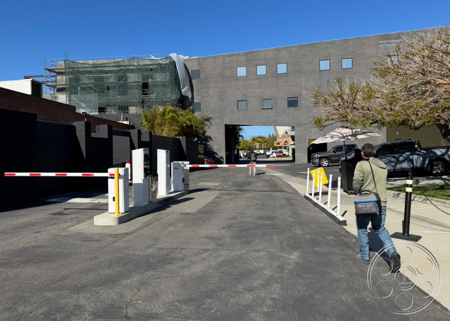Hayden Tract - urban setting, commercial space, asphalt driveway, open parking area, flat roof design, rectangular building shape, concrete boundary wall, city backdrop, modern industrial architecture, black brick exterior wall, glass facade details, steel security gate, scaffolding for construction, exterior construction site, exterior landscape with trees