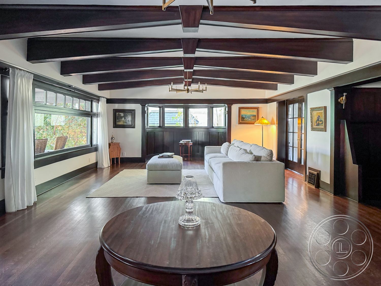 Craftsman 20 - cozy seating arrangement, floor-to-ceiling windows, dark wood paneling, textured fabric curtains, exposed wood ceiling beams, hardwood living room floors, interior living room, white painted walls, artwork wall decor, modern sofa upholstery, glass table accents, mid-century modern architectural details
