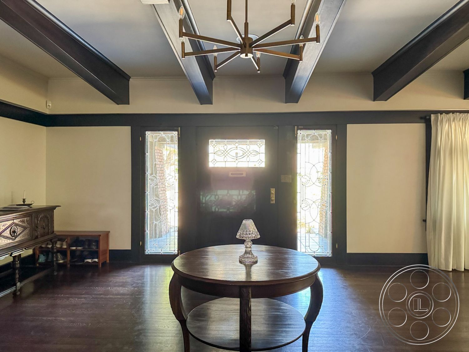 Craftsman 20 - interior dark wood paneling, interior hardwood living room floors, interior exposed wood ceiling beams, interior traditional entryway, interior glass front door, interior decorative light fixture, interior ornamental glass sidelights, interior round wooden entry table, interior white draped curtain, interior antique wooden furniture