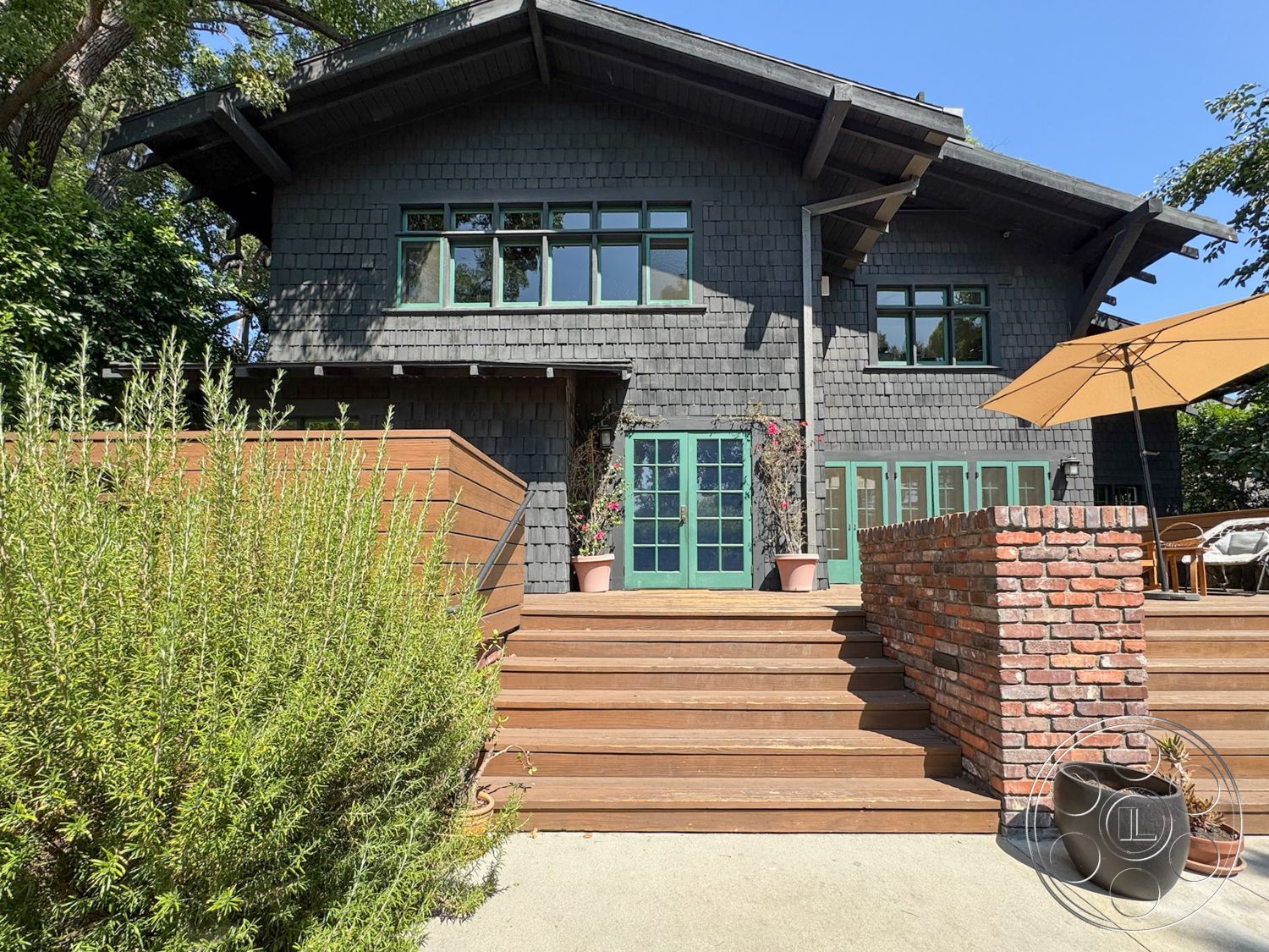 Craftsman 20 - exposed wooden beams, outdoor living space, natural wood finishes, arched doorway, urban residential setting, modern patio furniture, two-story home, landscaped garden setting, hardwood deck flooring, exterior wooden deck, contemporary home design, exterior red brick garden wall, dark wood shingle siding, green framed windows, textured wood steps, minimalist outdoor umbrella, lush greenery surrounds, rustic garden elements
