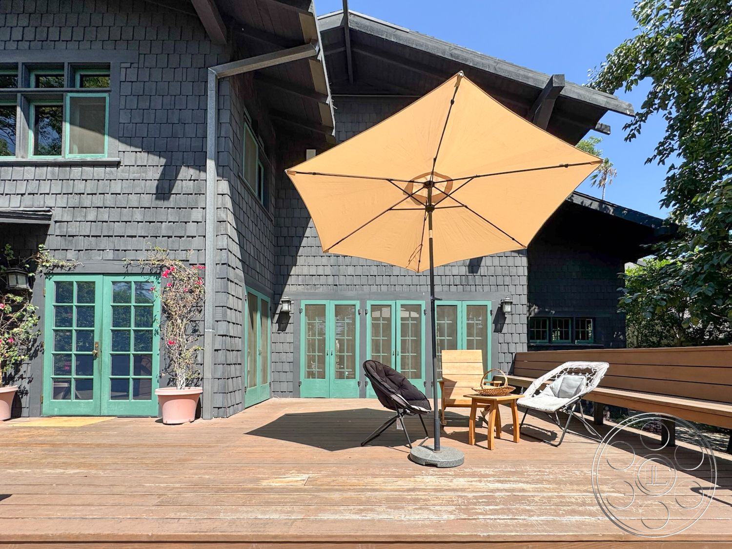 Craftsman 20 - urban backyard, exposed structural elements, landscaped garden setting, wooden deck flooring, exterior wood deck, rustic outdoor furniture, shingle-clad exterior walls, green double french doors, outdoor wood seating, canvas patio umbrella, dark wood beam roof, modern Craftsman style, interior space with natural light, suitability for outdoor entertaining