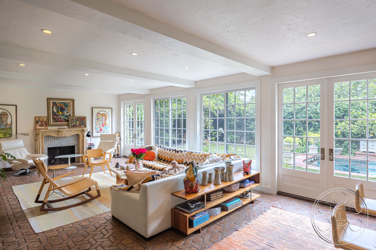 Mansion 2 - natural light, textured area rug, transom windows, contemporary furnishings, casual dining space, artistic decor elements, open living space, outdoor pool view, built-in bookshelves, wooden rocking chair, lush garden setting, wood beam ceiling, framed artwork on walls, glass French doors, exposed painted plaster walls, brick living room flooring, modern sofas, sectional seating area, vintage ceramic vases