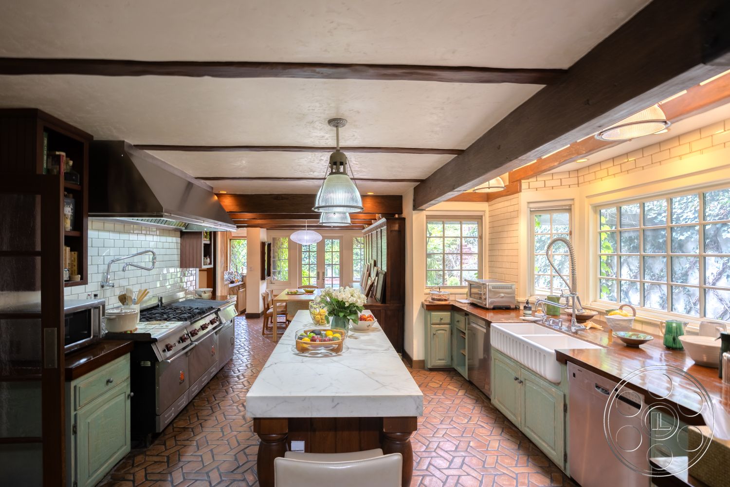 Mansion 2 - exposed wood ceiling beams, interior kitchen with marble countertop, white subway tile backsplash, dining area adjacent to kitchen, tile kitchen flooring with patterned design, stainless steel commercial range, glass window with garden view, wooden kitchen cabinets with vintage finish, large farmhouse sink with dual faucets, pendant lighting fixtures above kitchen island, open floor plan kitchen with dining area, light-filled kitchen with multiple windows, rustic kitchen with a welcoming ambiance, handcrafted wooden dining table, green accents in kitchen decor