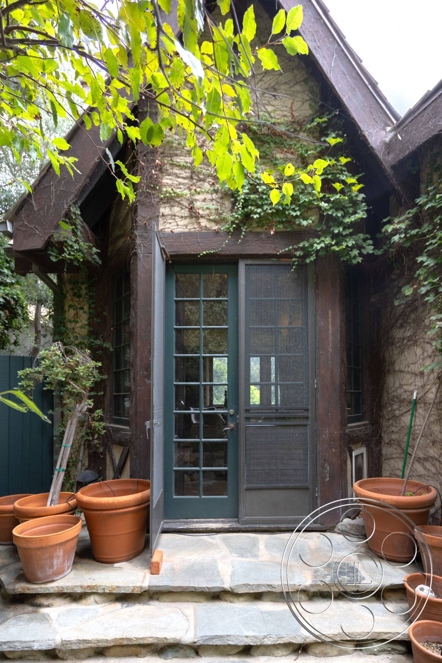 Mansion 2 - exterior stone patio flooring, exterior landscaped garden setting, exterior ivy-covered walls, exterior flagstone steps, exterior wooden door with grid panels, exterior natural stone wall treatment, exterior terracotta flower pots, exterior rustic wood beam accents, exterior gabled roof design, exterior green wood window frames