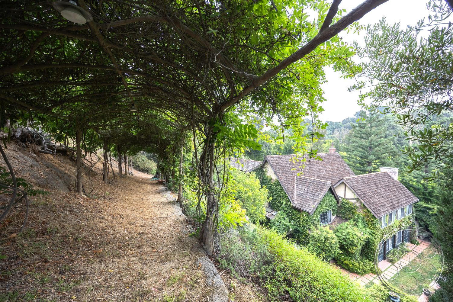 Mansion 2 - exterior, natural landscaping, sloped terrain, urban garden, wooden pathway, ivy-covered walls, patio space, craftsman architectural style, shingle roof, two-story home, arched trellis, front yard garden, stone paver walkway, forest setting, wood beam ceilings, covered outdoor pathway, vintage exterior lighting, greenery overhang, rustic home details