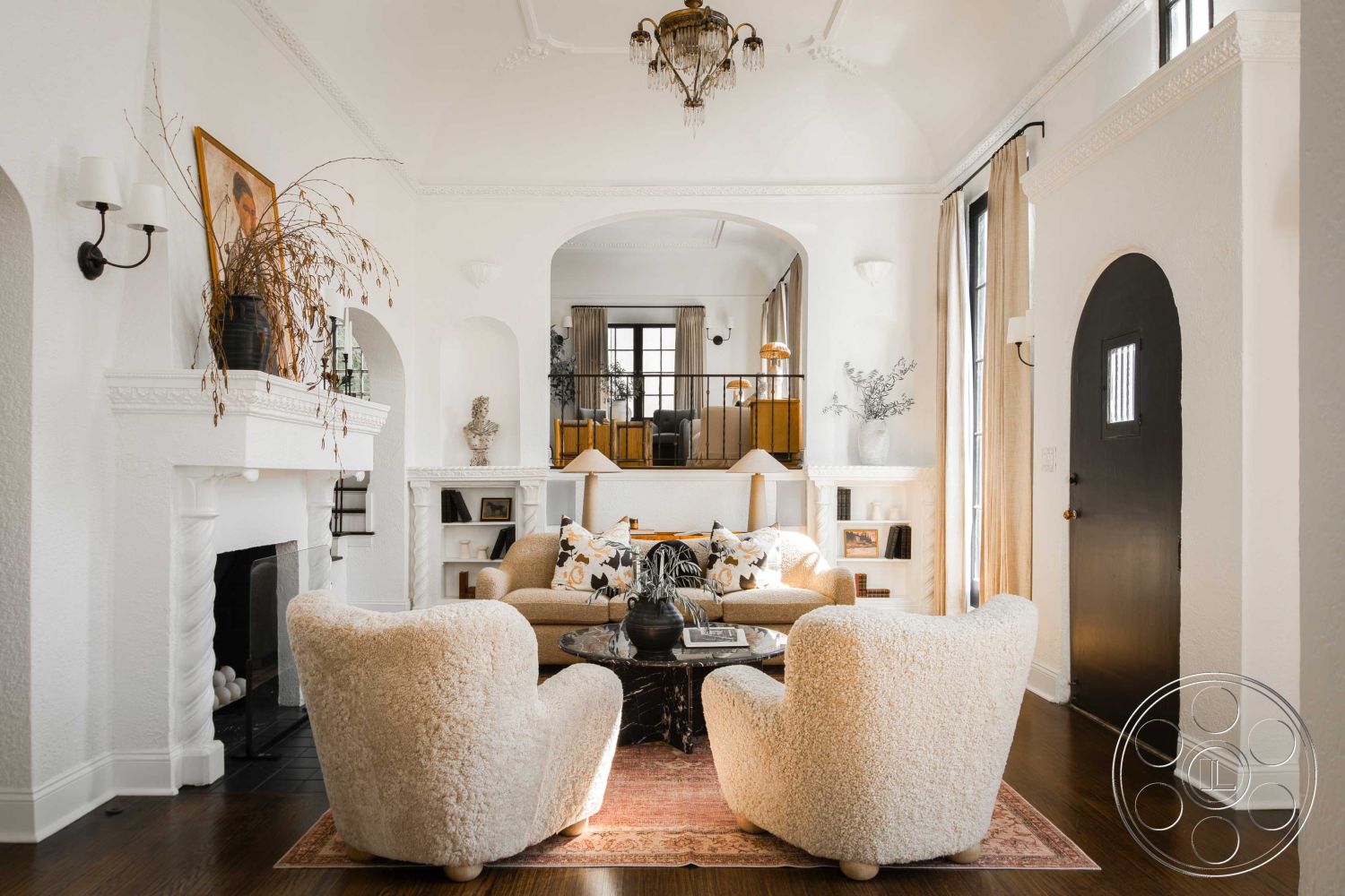 Spanish 166 - columns, neutral color palette, artistic wall decor, textured fabric cushions, white plaster walls interior, decorative indoor plants, large floor-to-ceiling windows, vintage chandelier, crown molding details, open floor plan living space, natural light-filled room, dark hardwood floors living room, arched doorway interior, cozy seating area with fluffy chairs, modern rustic accents, Wall Sconces, white fireplace, multilevel