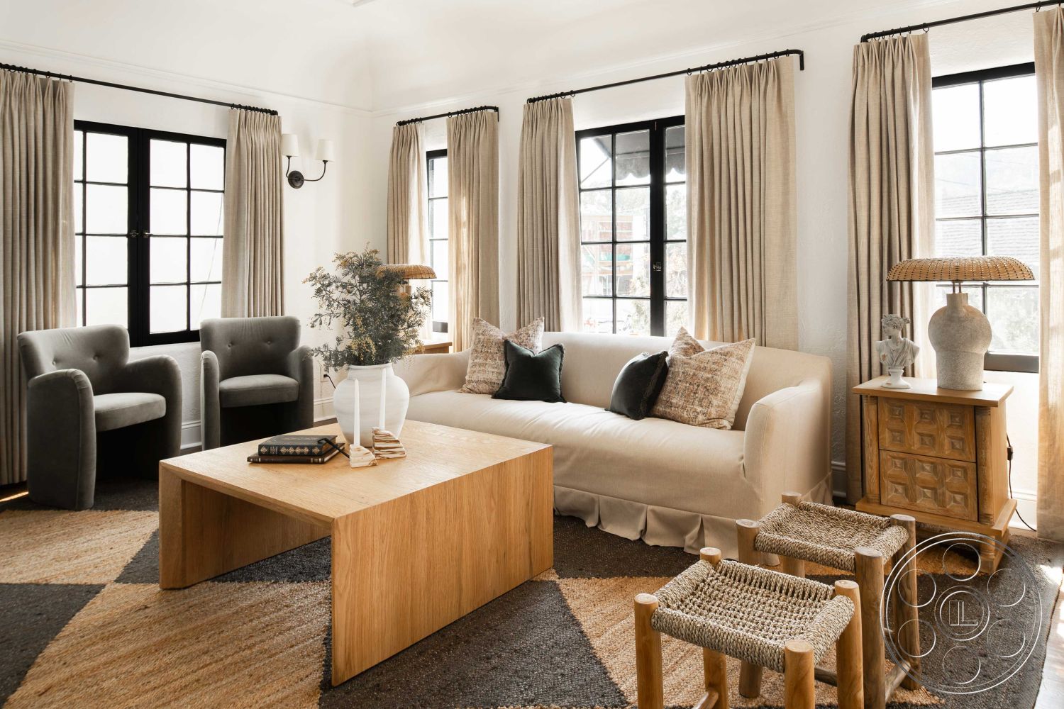Spanish 166 - neutral color palette, textured plaster walls, decorative ceramic vase, interior living room, large windows with black frames, hardwood floor accents, light beige curtains, contemporary fabric sofa, wood coffee table with clean lines, upholstered armchairs in gray, woven area rug with geometric pattern, wooden side table with geometric design, modern minimalist decor elements