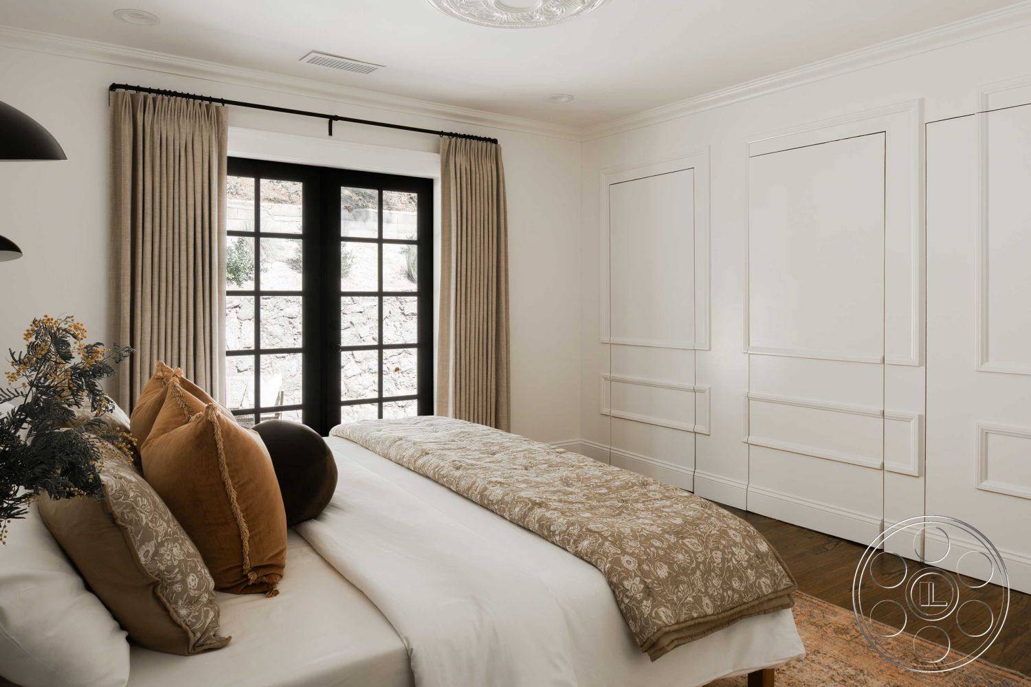 Spanish 166 - wainscoting, neutral color palette, textured bedding, black window frames, white painted walls, hardwood bedroom floors, cozy bedroom setting, traditional chandelier lighting, luxury bedroom interior, plush decorative pillows, vertical striped curtains, detailed crown molding, built-in closet cabinetry, ensuite