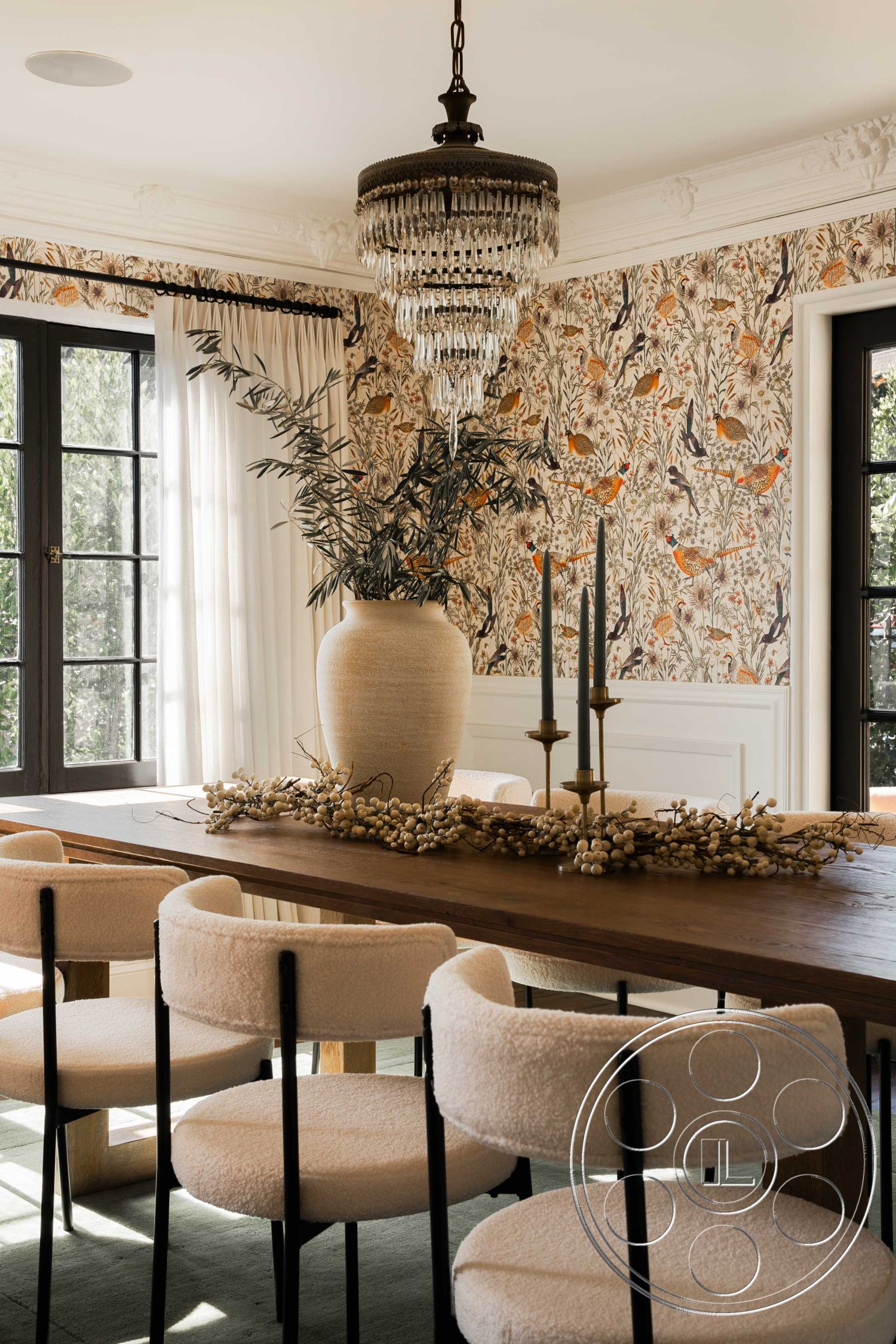 Spanish 166 - neutral color palette, natural light, contemporary style, candlestick holders, open space design, floral wallpaper, chandelier lighting, black window frames, velvet dining chairs, exposed wood ceiling beams, interior dining room, crown molding details, soft rug flooring, hardwood dining table, ceramic vase centerpiece, woven placemats, decorative foliage arrangement