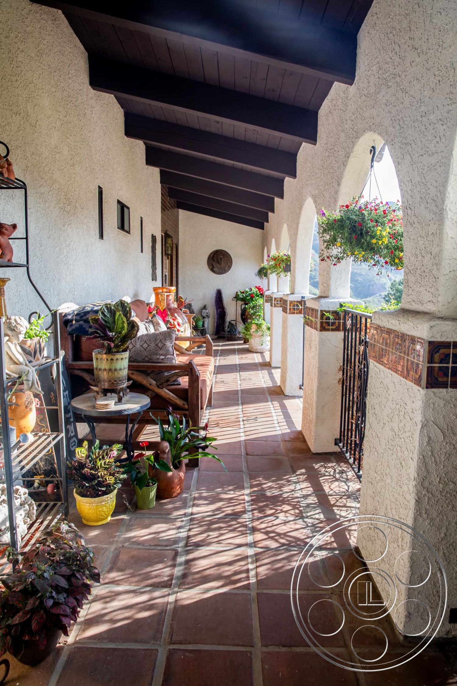 Medit 31 - natural light, exterior, landscape view, outdoor lounge area, arched doorways, Spanish-style architecture, terracotta tile flooring, decorative tile border, exposed wooden ceiling beams, stucco wall treatment, potted plants decor, iron railing details, Mediterranean courtyard