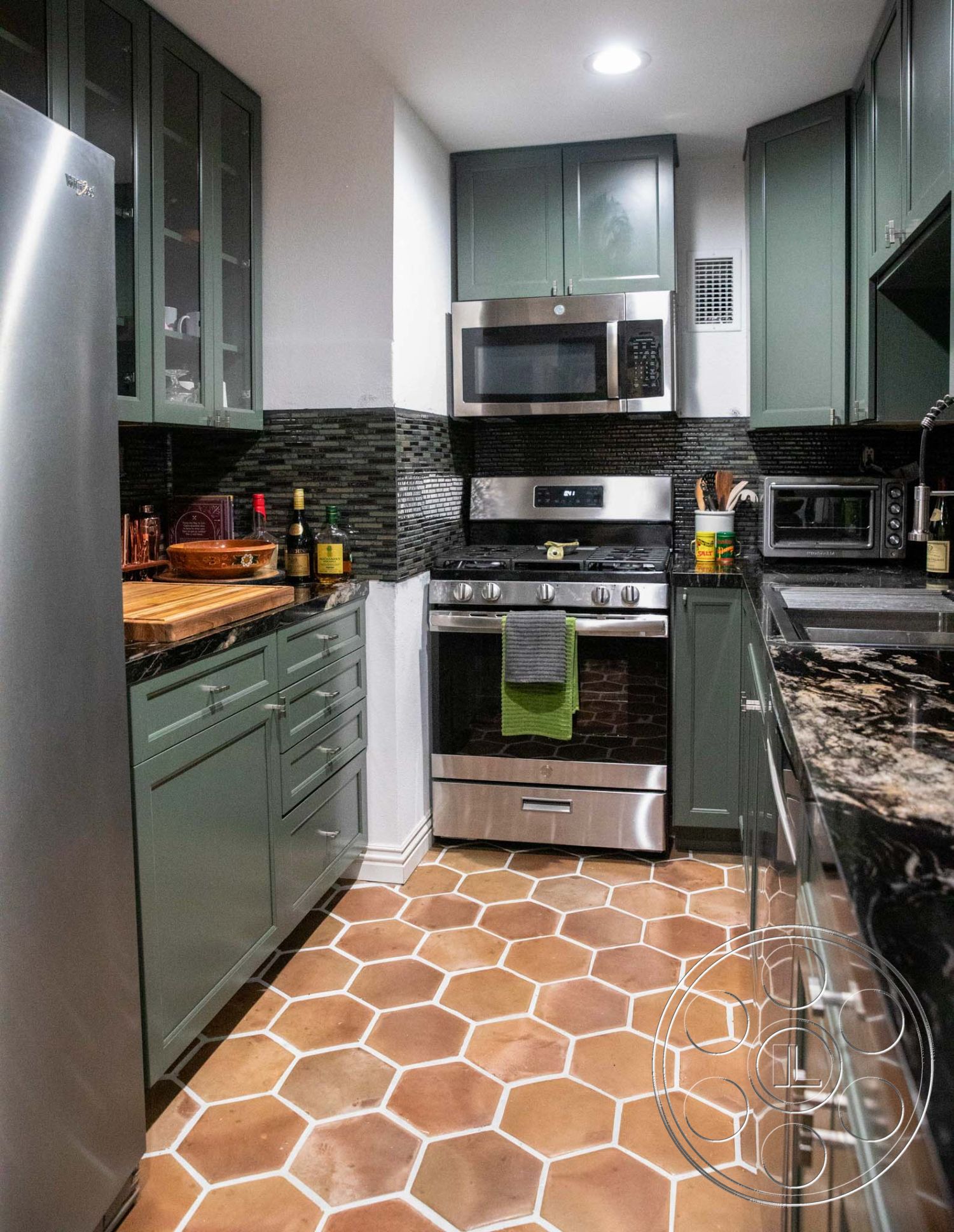 Medit 31 - stainless steel appliances, black granite countertops, modern kitchen design, open kitchen layout, recessed ceiling lighting, interior kitchen, hexagonal terracotta floor tiles, dark mosaic tile backsplash, green shaker-style cabinetry, wood cutting board countertop extension
