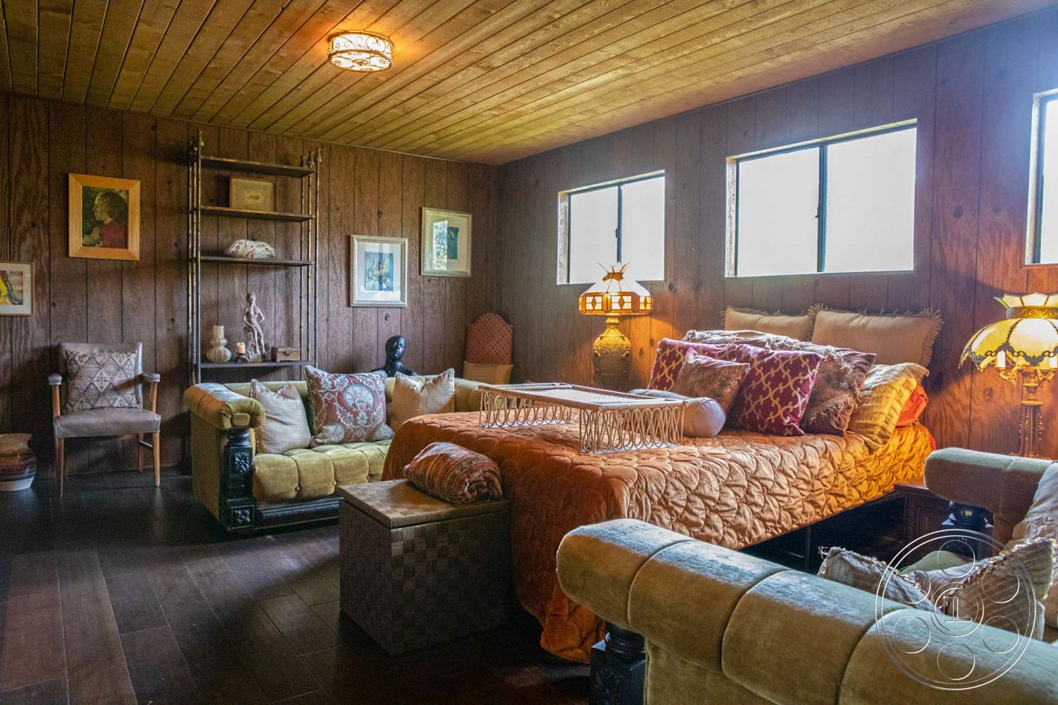 Medit 31 - interior hardwood flooring, interior wood paneling walls, interior warm color palette, interior textured ceiling, interior vintage-style lamps, interior upholstered seating, interior decorative pillows, interior wall art decor, interior open shelving unit, interior quilted bedspread, interior plush throw blankets, interior modest storage ottoman, interior multi-surface seating, interior casual living room setting