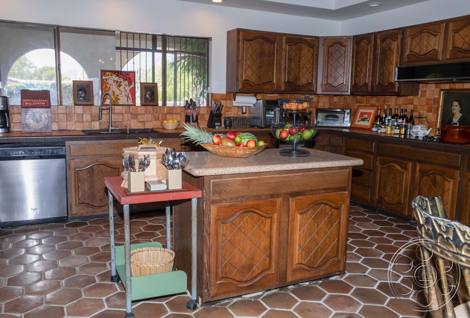 Medit 31 - dark wood cabinetry, stainless steel appliances, casual dining atmosphere, decorative tile backsplash, wooden dining chairs, earth-tone color palette, interior kitchen space, open kitchen layout, ceramic tile kitchen floor, hexagonal tile pattern, granite countertop island, decorative fruit bowl centerpiece, arched kitchen windows, modern kitchen lighting, exposed wood cabinet details, kitchen utility cart, rustic kitchen style