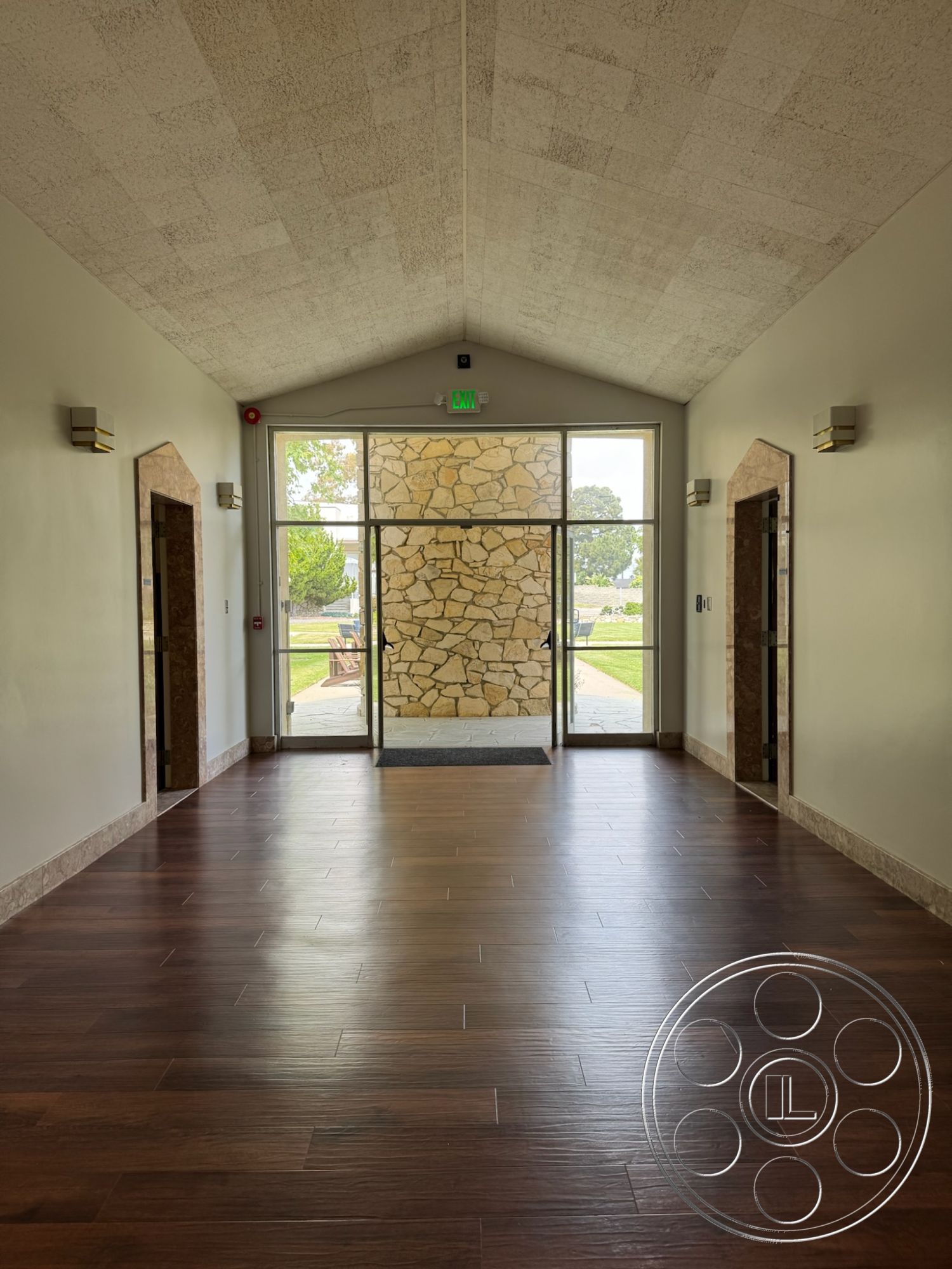 School 1 - interior open concept layout, interior recessed lighting fixtures, interior minimalist design elements, interior clean lines architecture, interior hardwood entryway flooring, interior textured plaster ceiling, exterior natural stone accent wall, exterior glass double doors, exterior landscaped outdoor view, interior modern elevator doors, interior smooth painted walls, interior stone border around entrance, exterior green lawn setting, interior transitional style