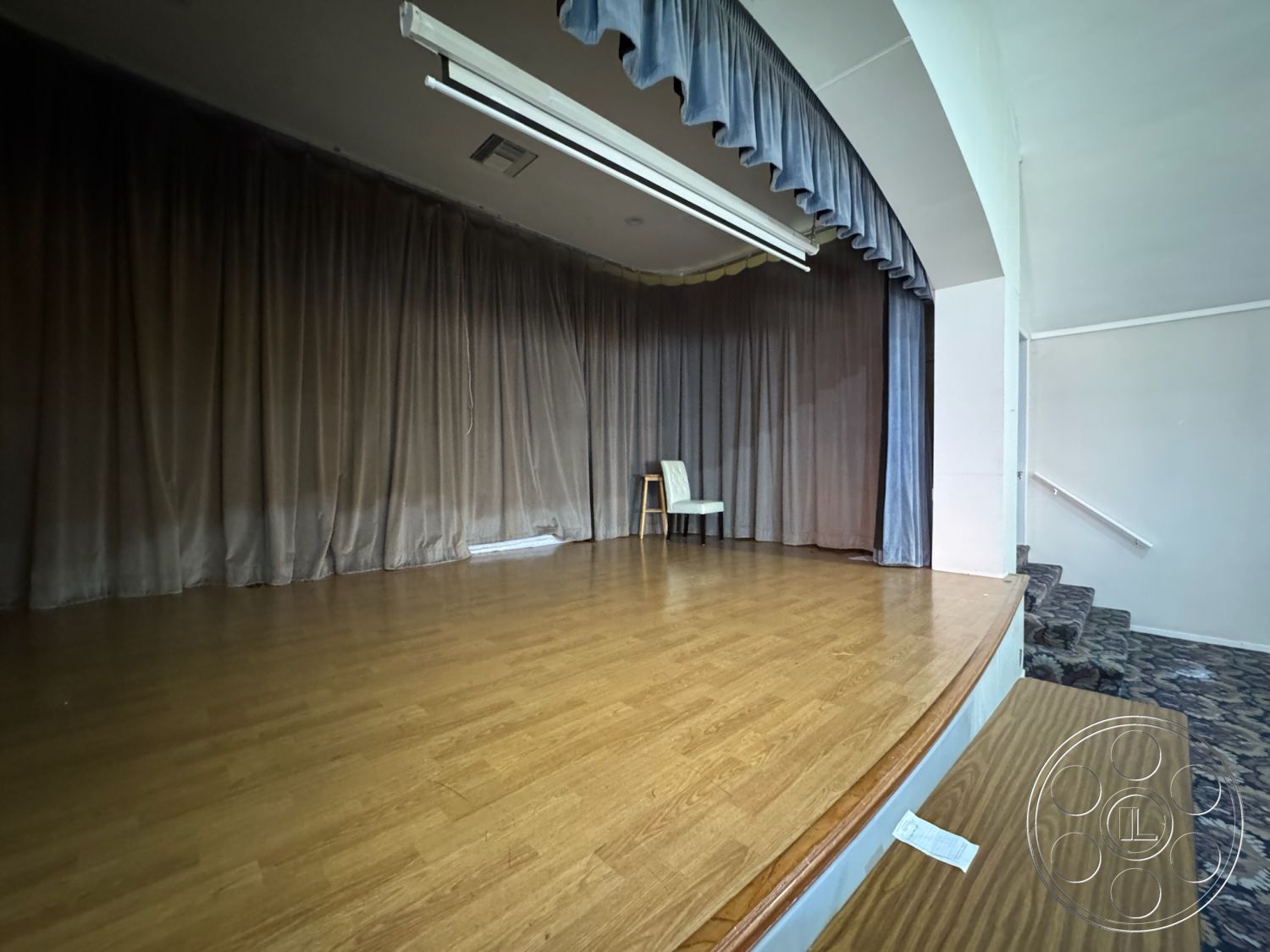 Spiritual Center - interior recessed lighting, interior hardwood stage floor, interior velvet stage curtains, interior theater seating stairs, interior simple wooden chair, interior acoustic paneling, interior rounded stage design, interior decorative carpet flooring, interior white-painted walls, interior backdrop space, interior performance venue