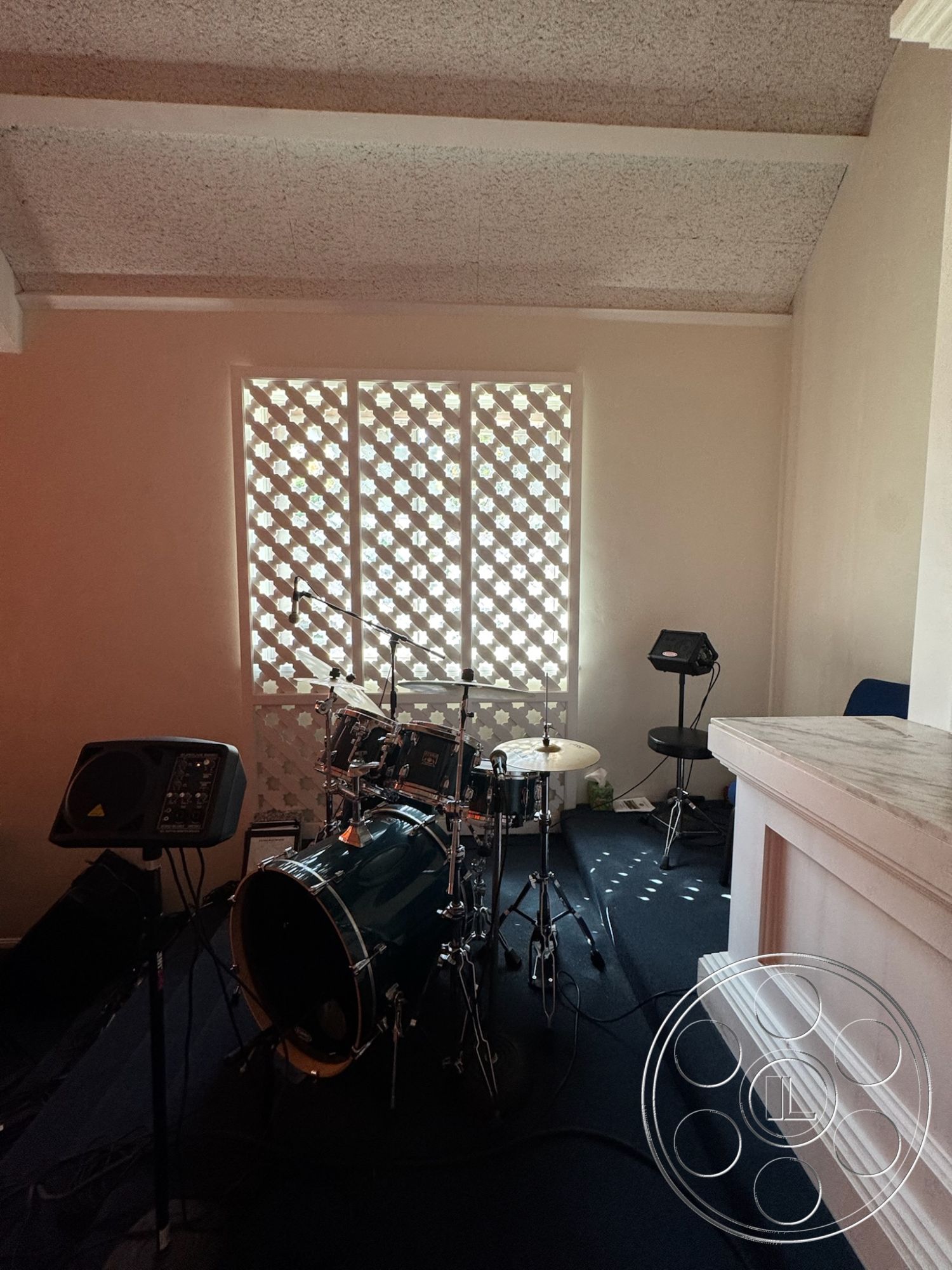 Spiritual Center - light-colored walls, interior space, soft ambient lighting, sound equipment, multi-purpose room, modernist design elements, textured ceiling panels, black carpet flooring, drum set, decorative lattice window screens, acoustic treatment features