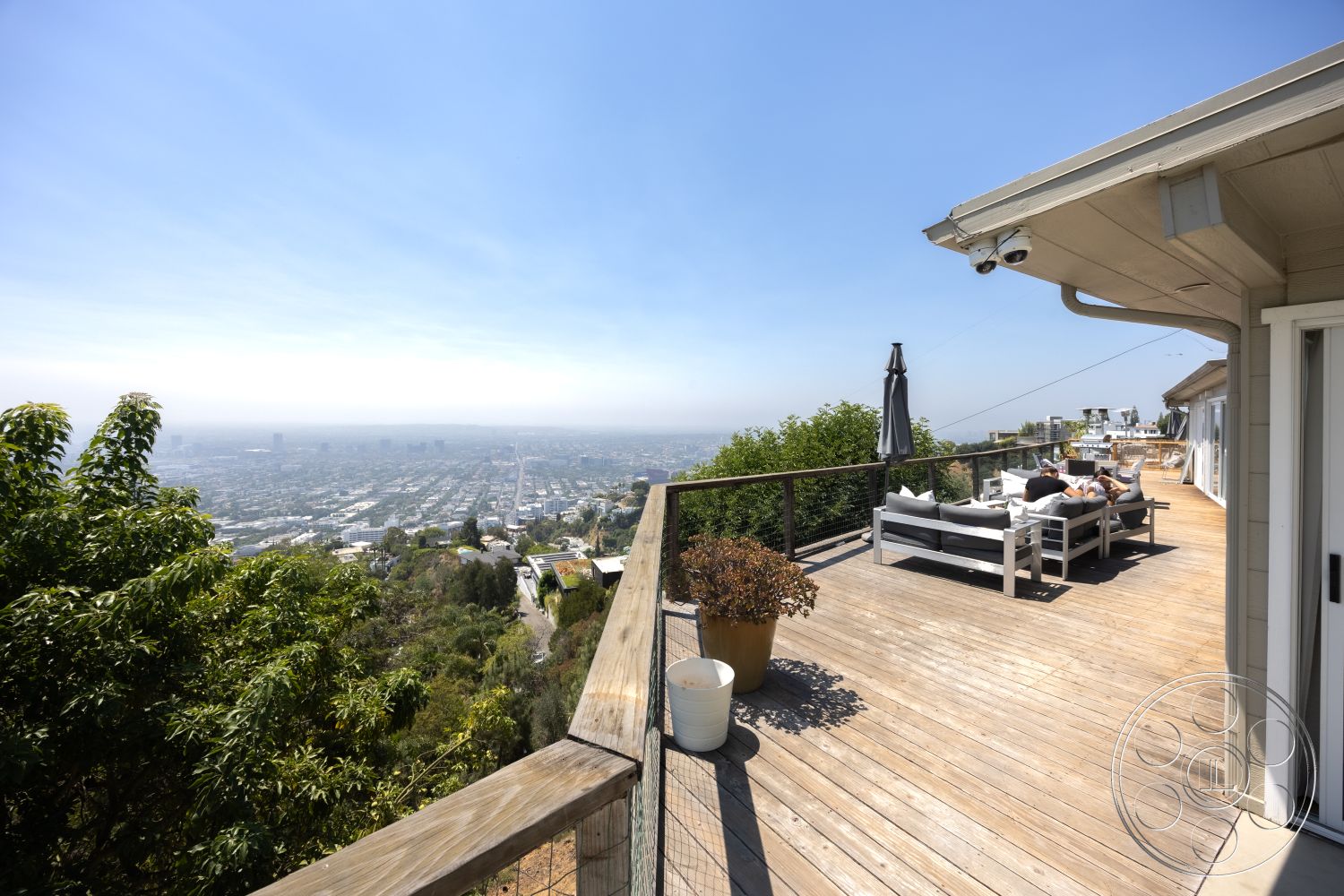 Retro 294 - natural wood finishes, urban skyline view, sunny outdoor area, open-air lounge, glass sliding door, wooden deck flooring, exterior wooden deck, modern outdoor seating area, potted plants decor, landscaped garden surroundings, metal railing system, contemporary patio design, mountainous hillside location, attached roof overhang, relaxed leisure space