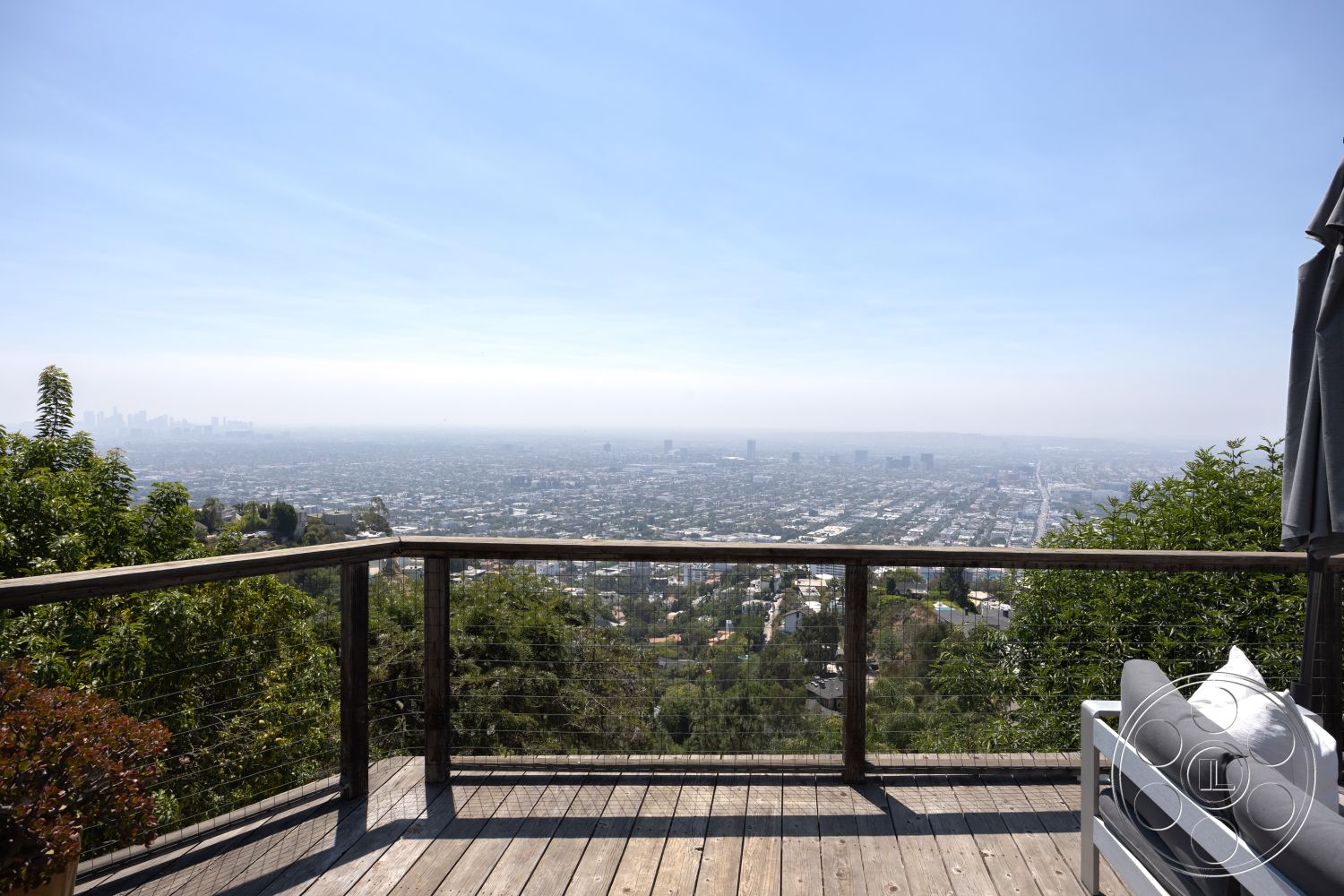 Retro 294 - surrounding greenery, exterior landscaping, outdoor living space, natural wood finishes, modern architectural style, city skyline view, panoramic city view, contemporary outdoor seating, hilltop location, wood deck patio flooring, open-air balcony, metal cable railing, aluminum deck furniture, sunny weather environment