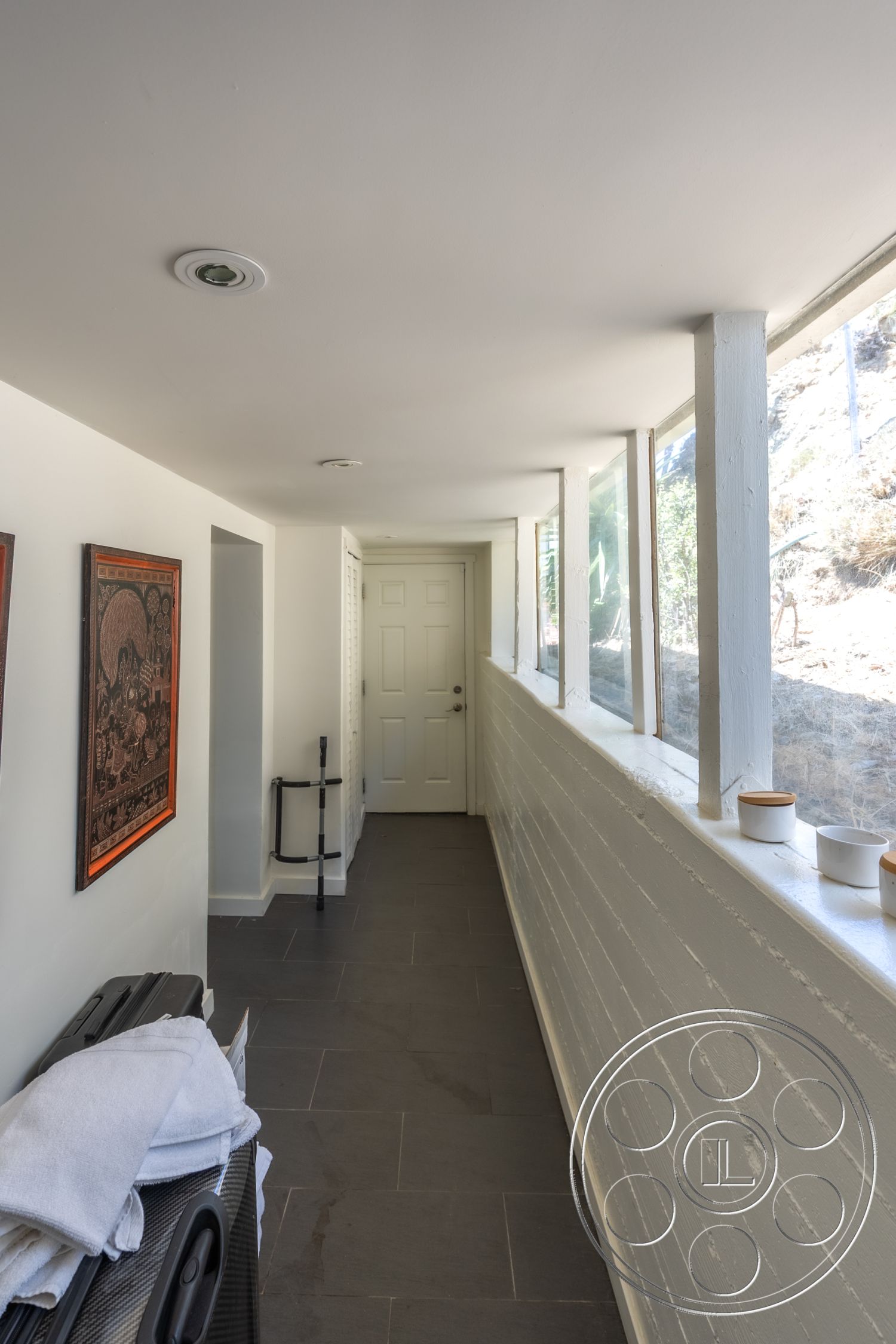 Retro 294 - neutral color palette, clean lines, artwork on walls, large floor-to-ceiling windows, simple geometric shapes, slate tile flooring, interior hallway, modern minimalist design, natural light-filled space, contemporary architectural details, smooth white painted walls, white wooden door