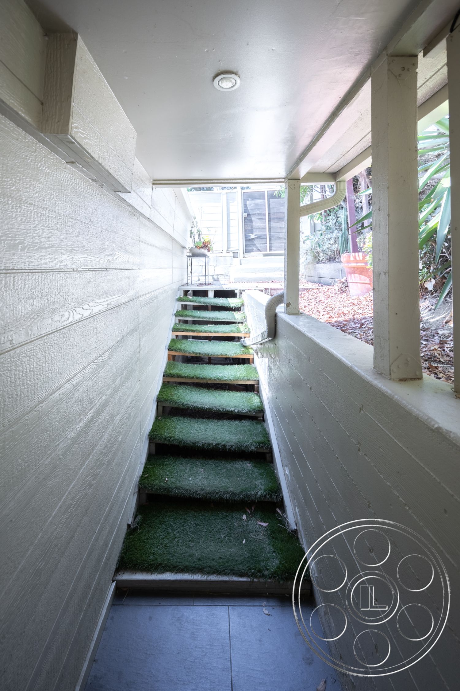 Retro 294 - exterior, surrounded by greenery, narrow passage, textured wood paneling, natural light entryway, landscape setting, artificial grass stair treads, stone textured flooring, outdoor stairway, sloped entrance