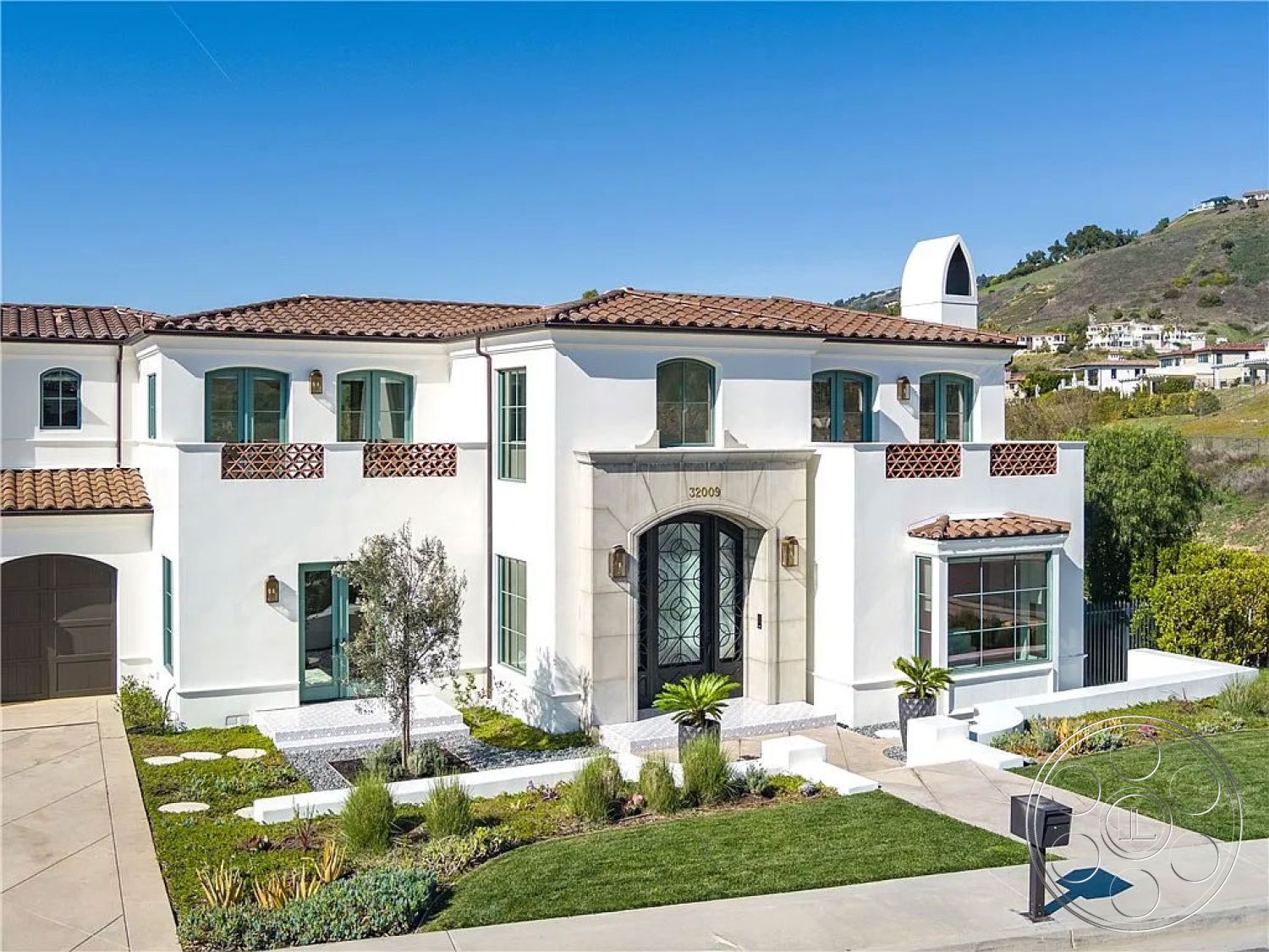 Spanish 167 - exterior, curved pathway, stucco walls, arched doorways, terracotta tile roof, Mediterranean architectural style, landscaped garden with native plants, minimalist front yard design, decorative wrought iron entry door, large picture windows, wooden balcony railing, driveway with concrete pavers, corner lot home, front facade with symmetrical design, vaulted ceiling entryway