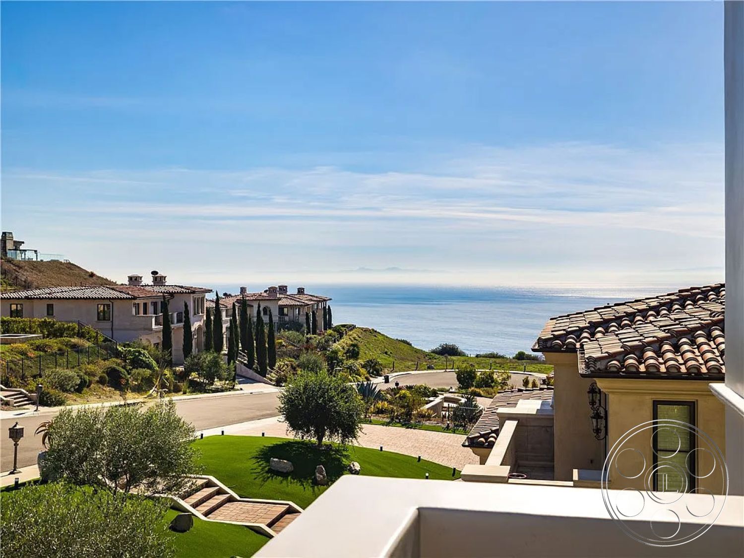 Spanish 167 - landscaped garden, paved driveway, green lawns, circular driveway, curved pathways, stucco walls, tile roof, sunny coastal setting, hillside location, Mediterranean architectural style, outdoor lighting fixtures, oceanfront property, exterior sea view, columnar cypress trees, lawn with ornamental plants, terraced garden layout, balcony with ocean view, patio with stone pavers, multi-story residence, walking paths