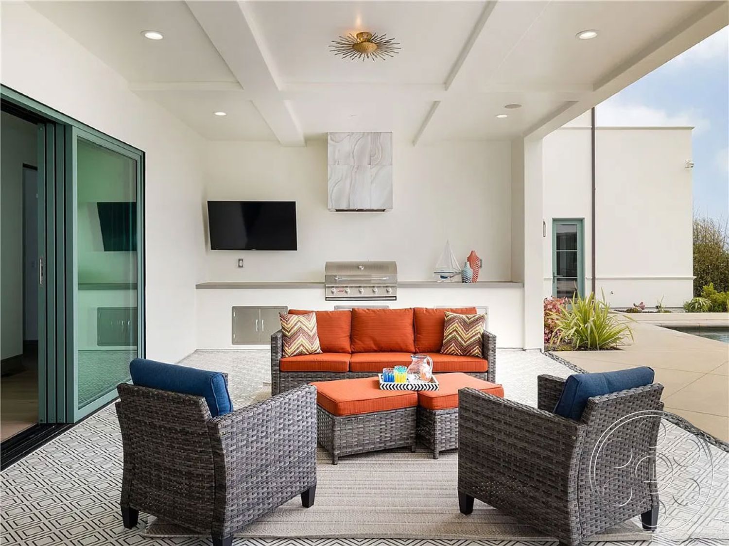 Spanish 167 - minimalist style, glass sliding doors, woven outdoor furniture, stainless steel grill, open-air design, recessed ceiling lights, urban outdoor retreat, stone patio flooring, contemporary design aesthetics, exterior patio seating area, orange outdoor cushions, outdoor kitchen setup, modern flat ceiling, decorative patterned rug, built-in TV wall mount, landscape garden elements, open plan entertaining space, bio-safe materials, sun-drenched seating area
