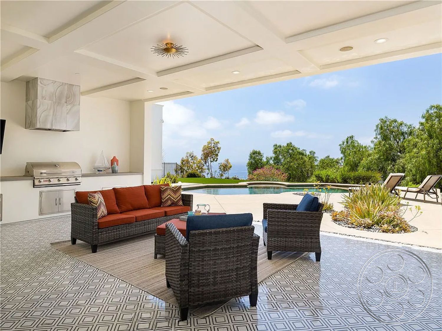 Spanish 167 - rectangular swimming pool, concrete pool deck, sunbathing lounge chairs, exterior patio space, lush landscaping with succulents, woven wicker outdoor furniture, modern outdoor kitchen with stainless steel grill, diamond-patterned tile flooring, detailed ceiling moldings, open concept outdoor living area, clear view of landscape with trees, poolside relaxation area, Mediterranean style setting