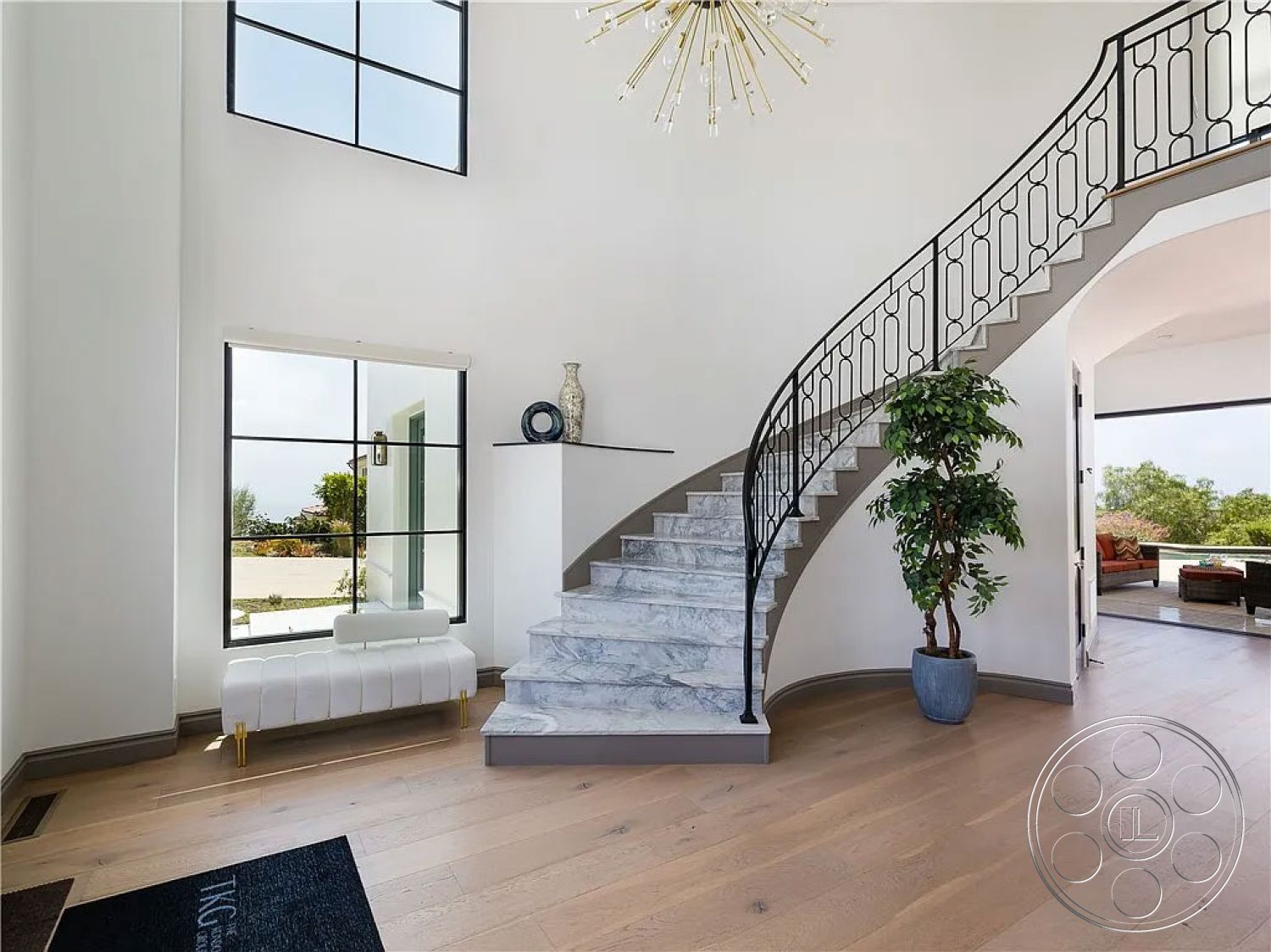 Spanish 167 - interior contemporary design, interior hardwood flooring, interior potted plant decor, interior white painted walls, interior open floor plan, interior minimalist furniture, interior geometric shapes, interior curved staircase, interior marble staircase, interior glass window accents, exterior large windows, interior modern chandelier, interior black metal railing, interior natural light entryway, interior surrounding garden view