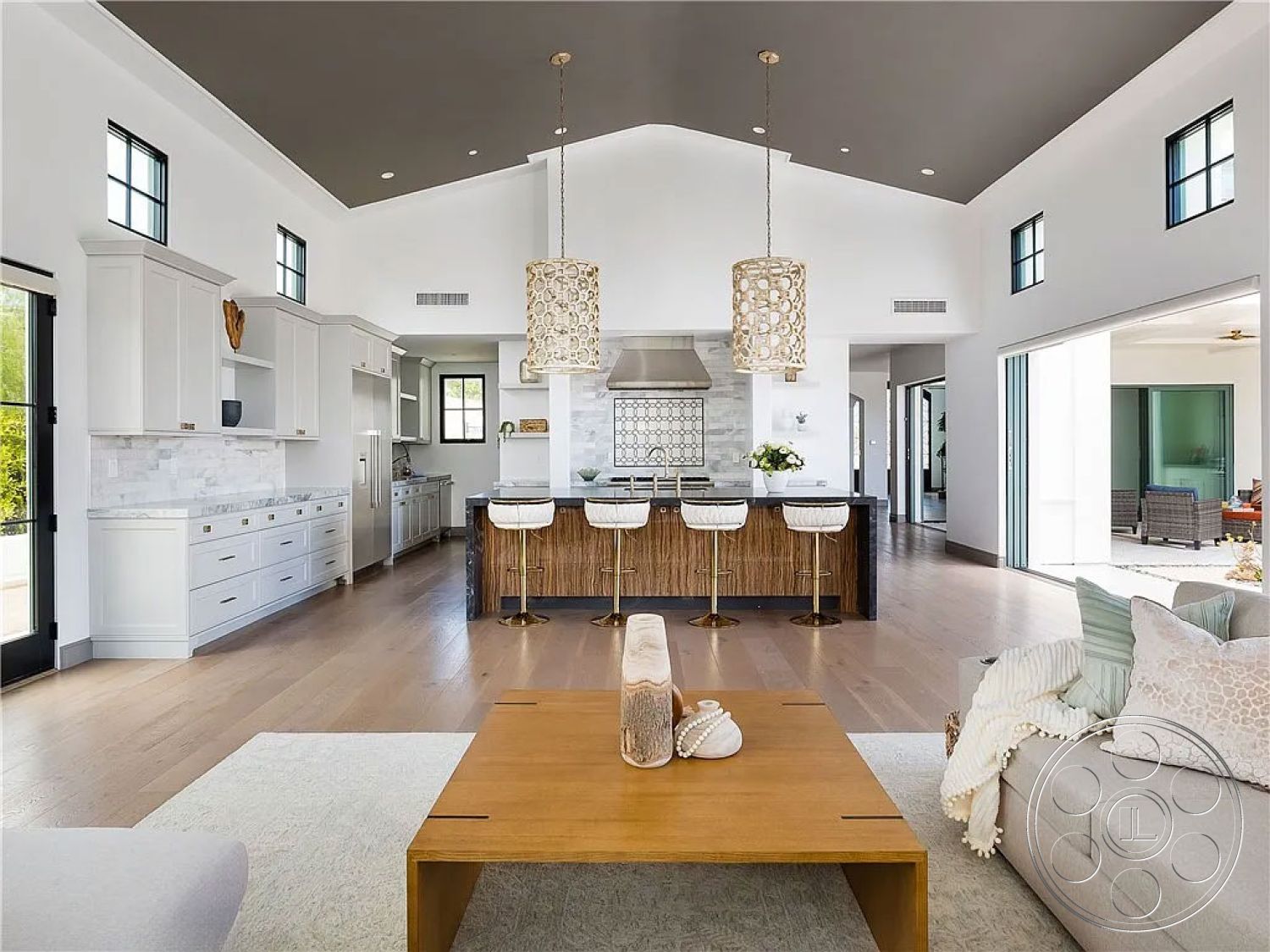 Spanish 167 - stainless steel appliances, modern coffee table, glass pendant lighting, designer light fixtures, marble kitchen countertops, minimalist decor elements, neutral colored area rug, open floor plan design, interior open-concept kitchen, white shaker kitchen cabinets, vaulted ceiling living room, hardwood flooring kitchen, textured ceiling with dark paint, stone kitchen backsplash, built-in bar stool seating, glass sliding doors leading to patio, cozy living area with sectional sofa, tropical outdoor patio view, island kitchen with seating, decorative wood accents, two-tone cabinetry in kitchen
