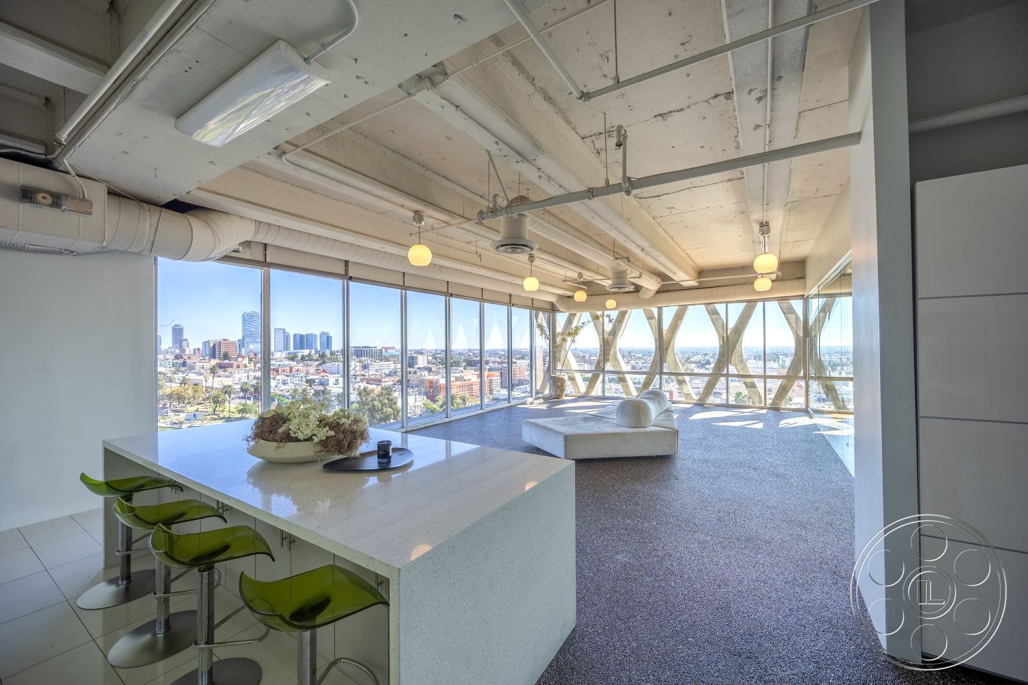 Loft 158 - quartz countertop, minimalist design, polished concrete flooring, urban skyline view, textured wall finishes, exposed concrete ceiling, modern kitchen island, modern lounge area, contemporary lighting fixtures, natural light-filled space, industrial style interior, concrete column supports, glass floor-to-ceiling windows, open-plan living area, city setting, translucent green bar stools, angular furniture shapes, white modular kitchen cabinetry, high-rise apartment interior