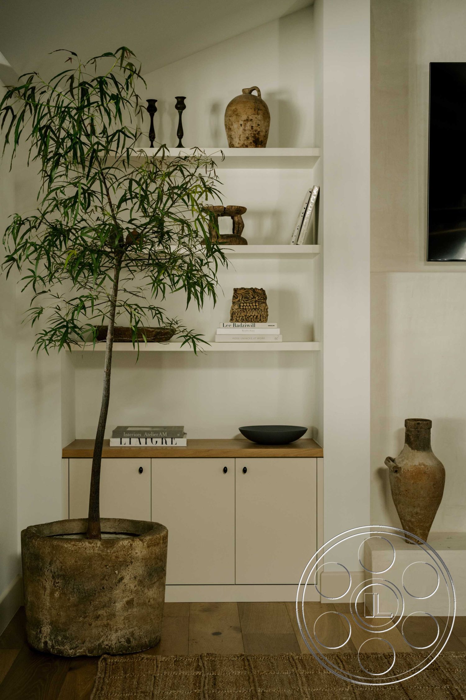 Americana 429 - light wood flooring, modern aesthetic, simple geometric shapes, exposed wood ceiling beams, natural fiber area rug, neutral painted walls, open shelving unit, natural stone planter, contemporary decor elements, ceramic decorative vases, succulent plant arrangement, minimalist design accent, black hardware details, clearly defined living space