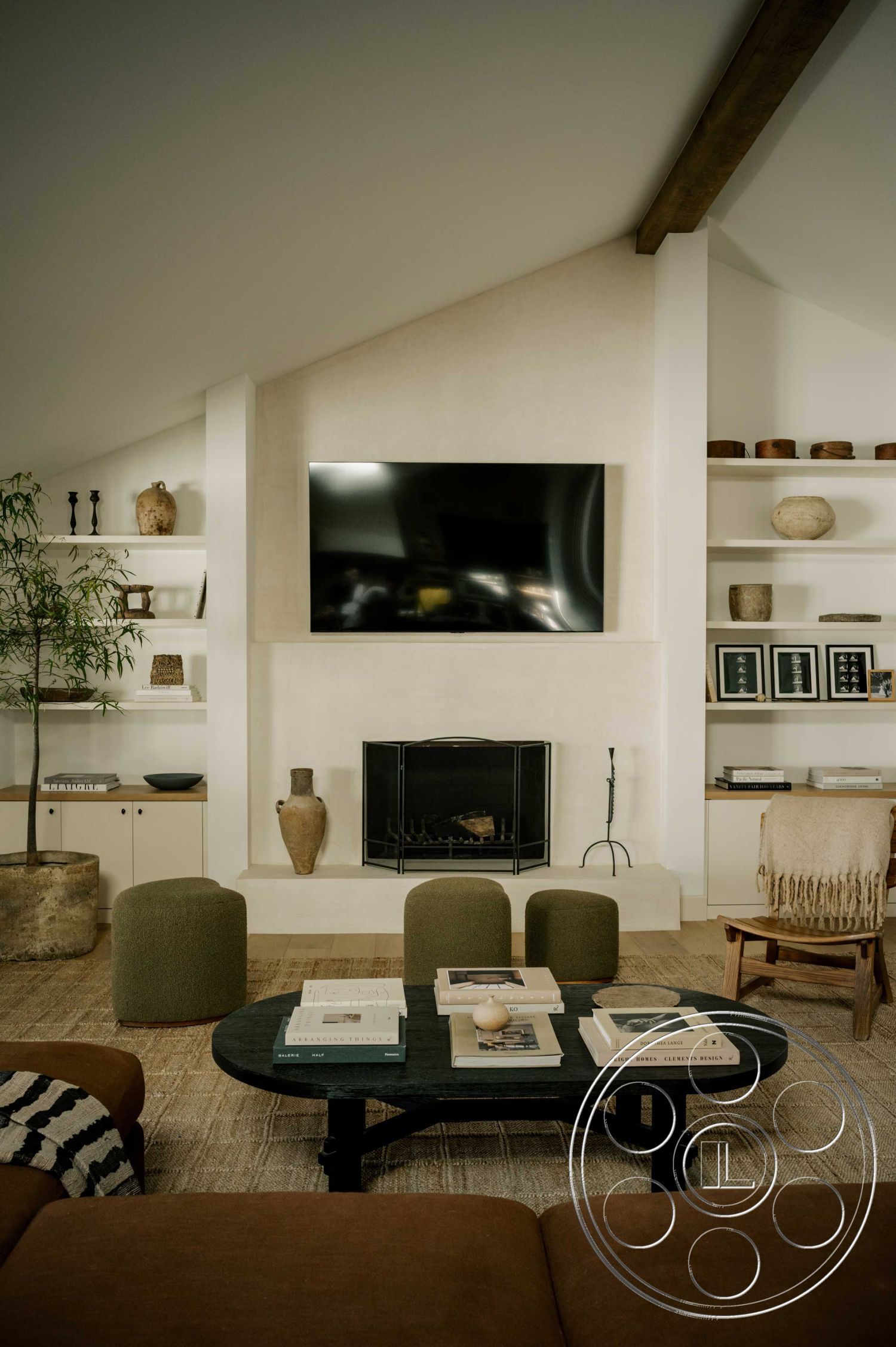 Americana 429 - minimalist decor, neutral color palette, textured accent wall, dark hardwood flooring, round wooden coffee table, contemporary lighting fixtures, exposed wood ceiling beams, interior living room, stone fireplace surround, soft wool area rug, upholstered lounge chairs, open shelving units, plastered fireplace wall, decorative clay vases, functional media console