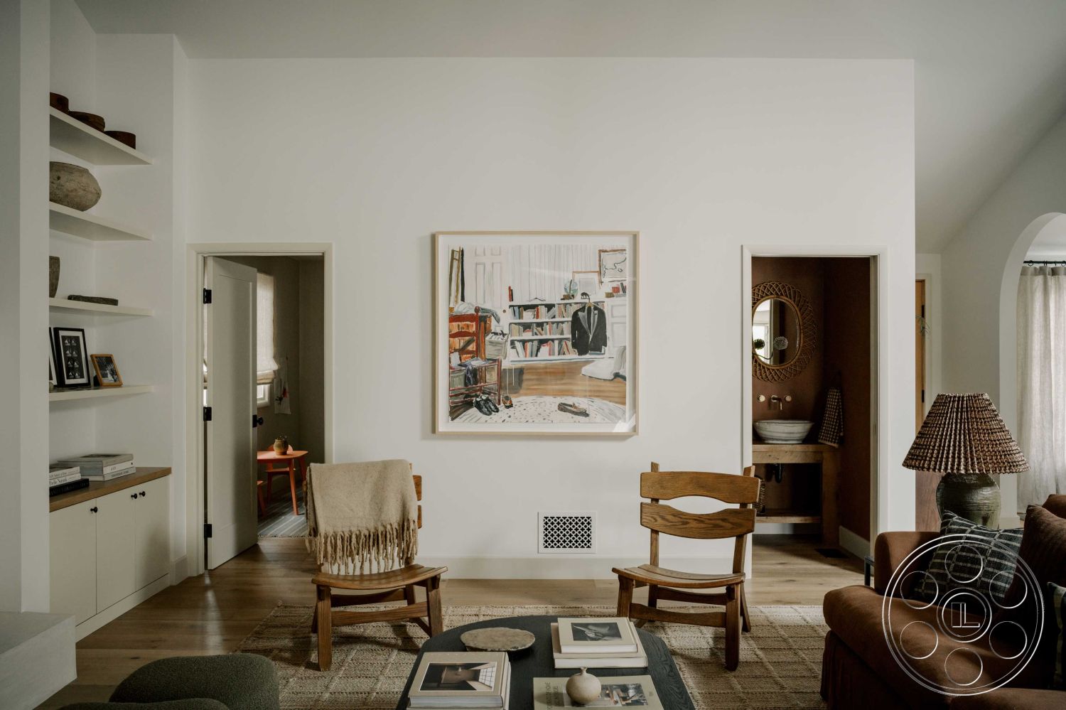 Americana 429 - minimalist decor, neutral color palette, open floor plan, light wood flooring, wooden dining table, interior space, wooden accent chair, natural light from windows, comfortable seating area, woven lamp shade, casual living room, white painted walls, textured wool area rug, framed art on wall, wood shelving units, arched doorway leading to bath, modern art accents, indoor plants as decoration