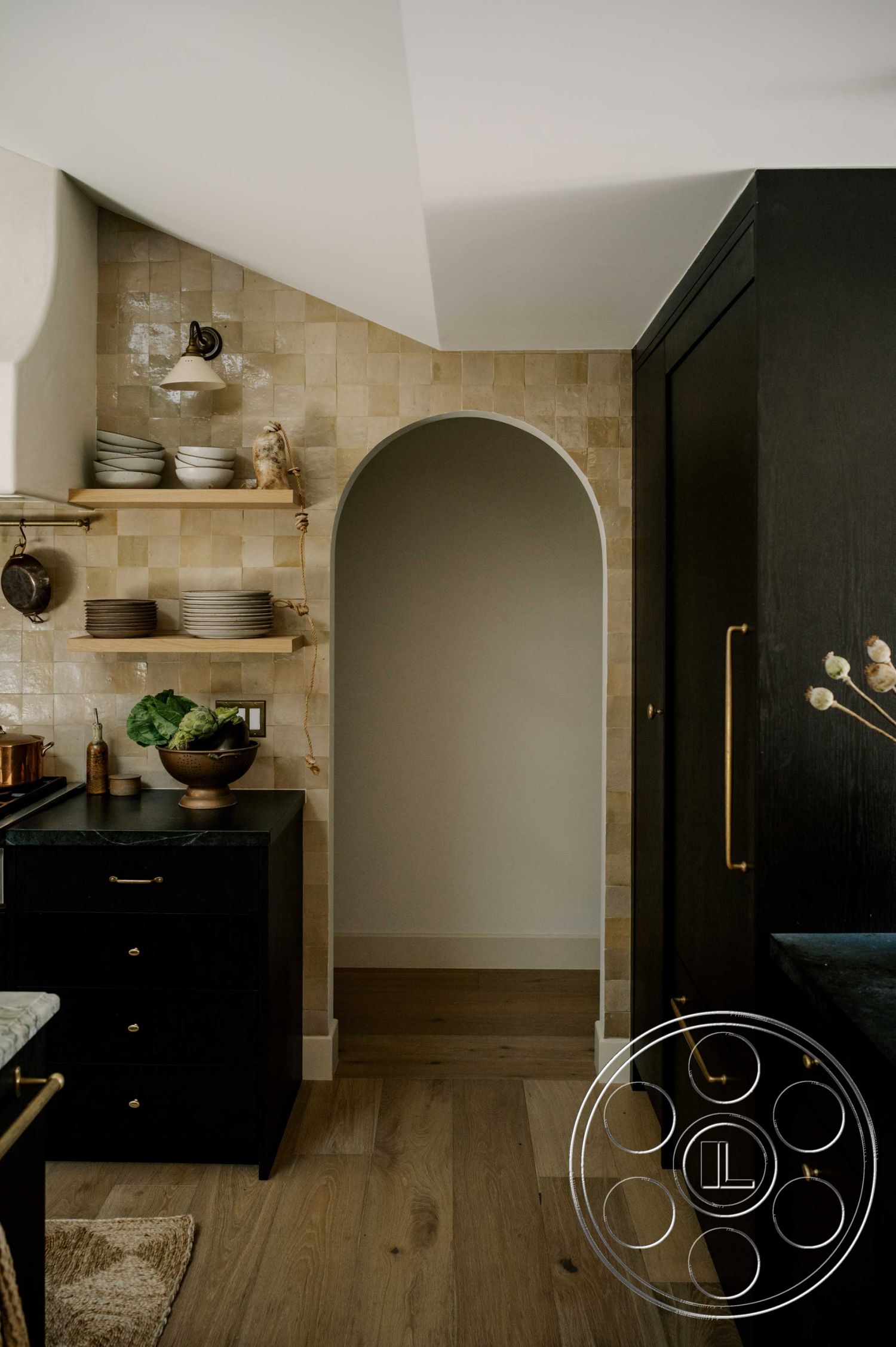 Americana 429 - neutral color palette, natural wood accents, open shelving, black cabinetry, stone countertop, arched entryway, functional kitchen layout, ambient lighting fixtures, textured tile backsplash, modern minimalist design, interior kitchen, brass cabinet hardware, wooden kitchen floors, elegant kitchen decor