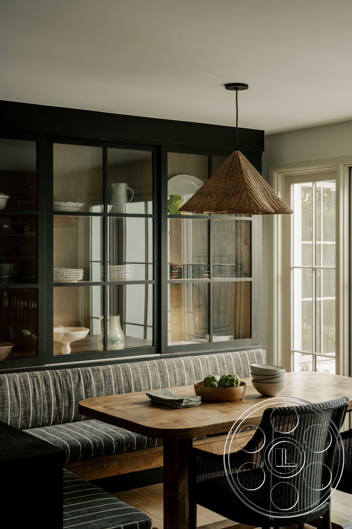 Americana 429 - soft neutral color palette, open floor plan, large windows for natural light, textured wall finish, casual dining space, comfortable seating arrangement, woven pendant light fixture, modern minimalist design, functional storage solutions, hardwood dining table, interior kitchen dining area, upholstered bench seating, black framed glass display cabinets, striped fabric upholstery, wooden accent elements