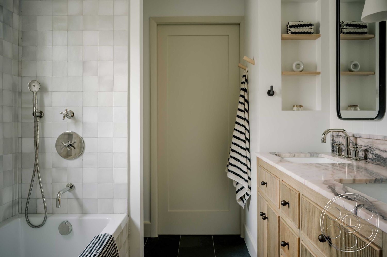 Americana 429 - neutral color palette, soft natural lighting, black slate flooring, interior bathroom design, chrome shower fixtures, contemporary bathroom style, white subway tile shower walls, marble bathroom countertop, open shelving for towels, freestanding bathtub with chrome faucet, textured wood cabinetry, minimalist bathroom accessories, modern mirror with black frame