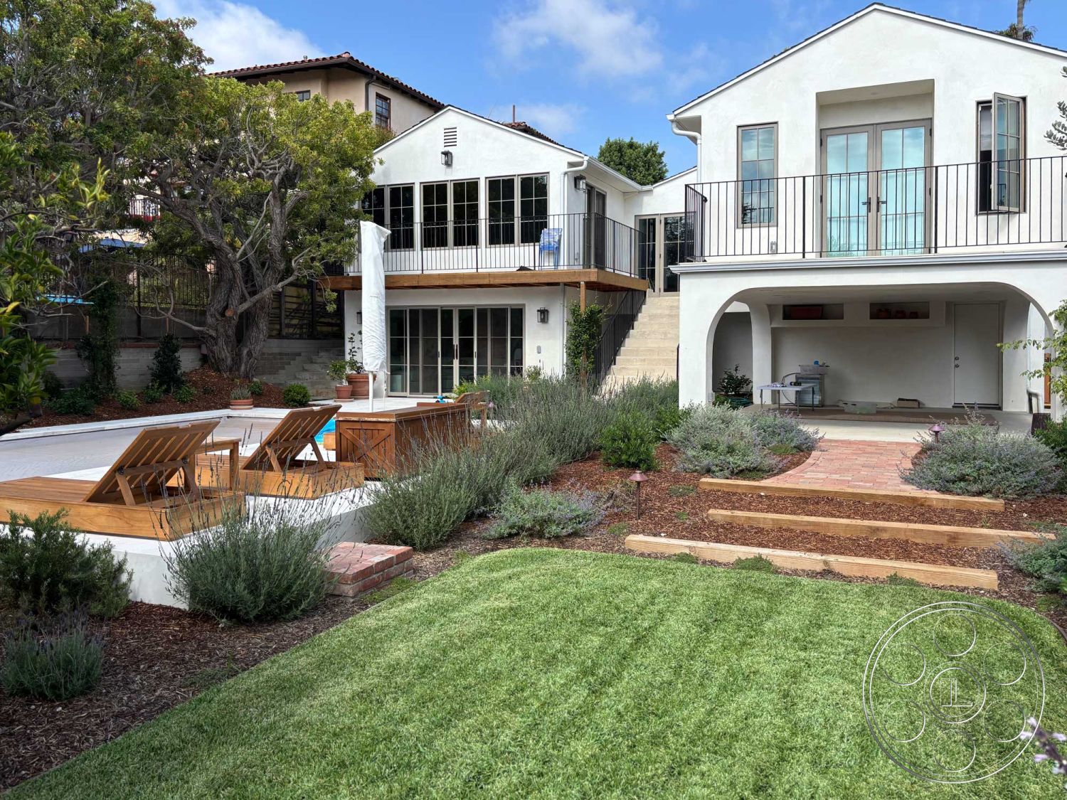 Americana 429 - exterior, glass sliding doors, rectangular swimming pool, grassy lawn, modern architectural style, wooden patio furniture, sunny outdoor setting, landscaped garden area, stucco house exterior, concrete pool border, decorative plantings, urban residential environment, wooden pool deck, brick stone steps, wooden railing balcony, multi-level backyard landscaping