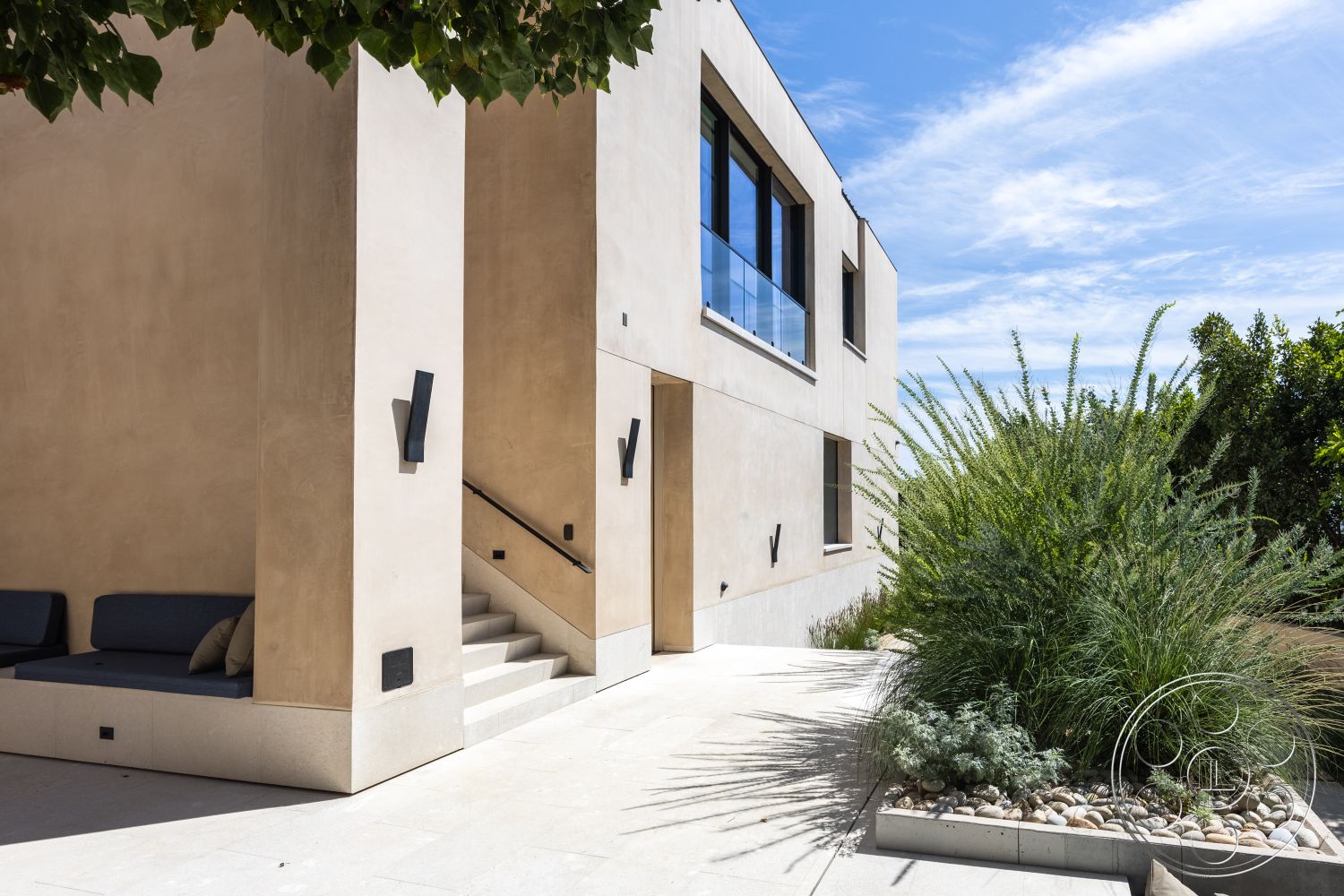 Modern 511 - neutral color palette, exterior, minimalist design elements, landscaped garden area, concrete patio flooring, smooth stucco wall finish, glass balcony railing, integrated outdoor seating area, sunny outdoor environment, concrete staircase, landscape with native shrubs, moderate architectural lines, flush-mounted wall sconces, cul-de-sac setting, urban residential property