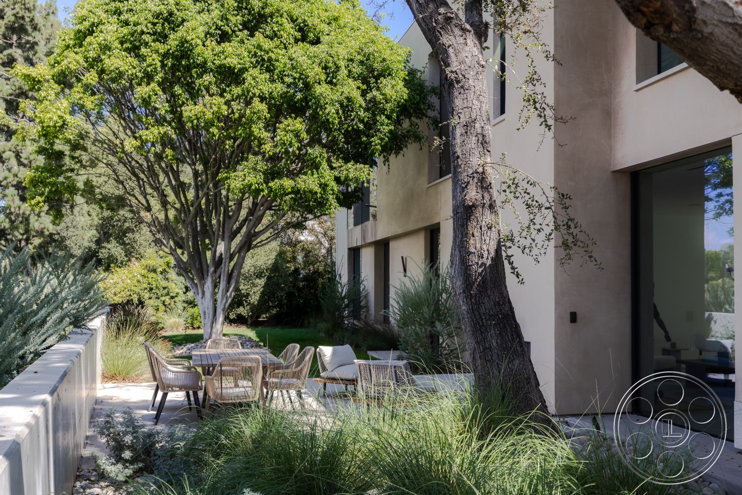 Modern 511 - floor-to-ceiling windows, metal outdoor furniture, urban garden, textured plaster walls, drought-resistant landscaping, concrete patio flooring, landscaped garden setting, modern outdoor dining area, rectangular patio, large shade tree, suburban residential environment, open backyard space, minimalist home exterior, natural stone edging