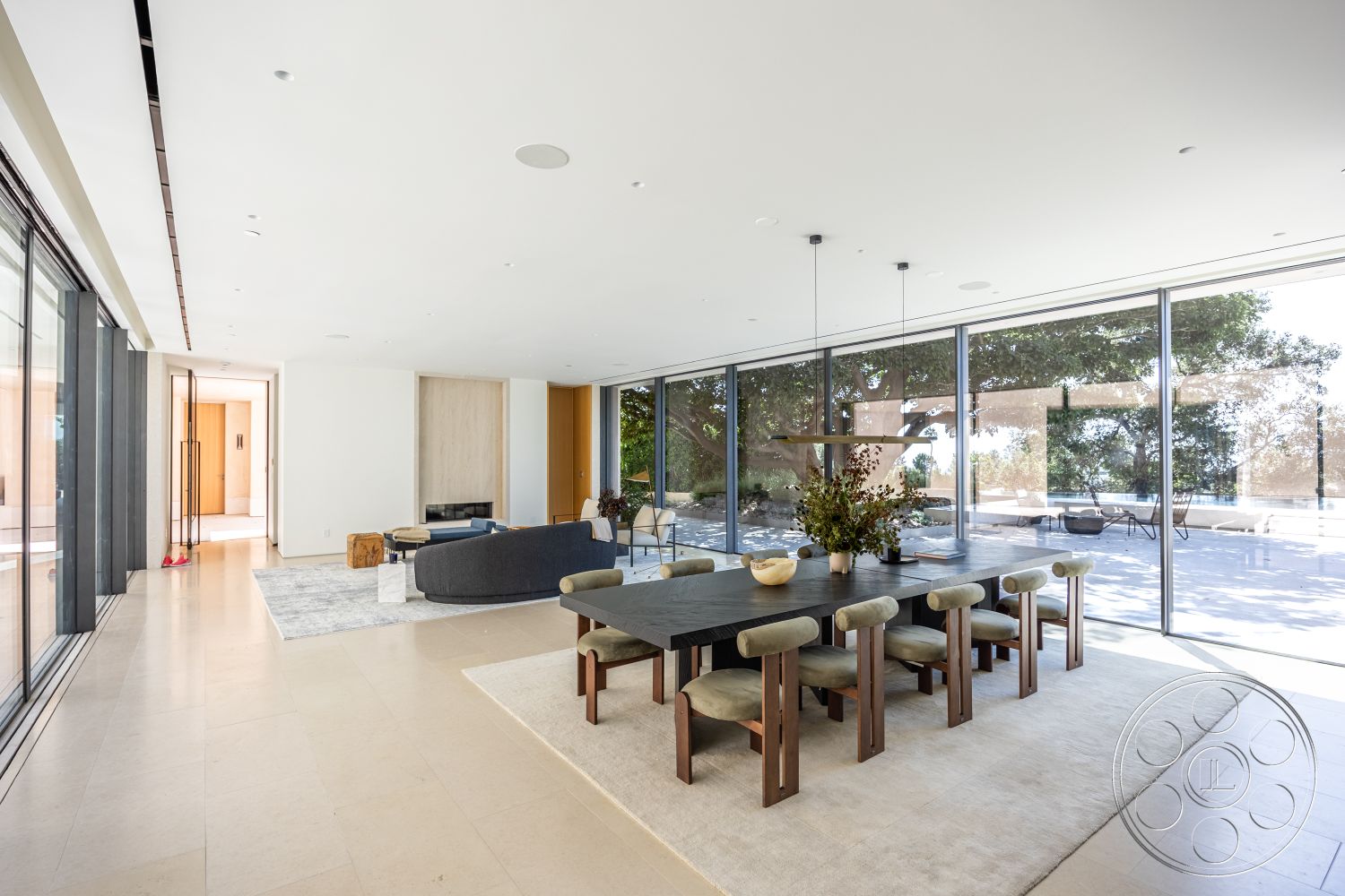 Modern 511 - neutral color palette, indoor plants, textured area rug, open floor plan, concrete flooring, upholstered dining chairs, modern coffee table, light wood cabinetry, minimalist dining area, stone fireplace surround, natural light from floor-to-ceiling windows, glass wall panels, contemporary art display, linear ceiling lights, dining table with wooden legs, view of outdoor patio, timber accent wall