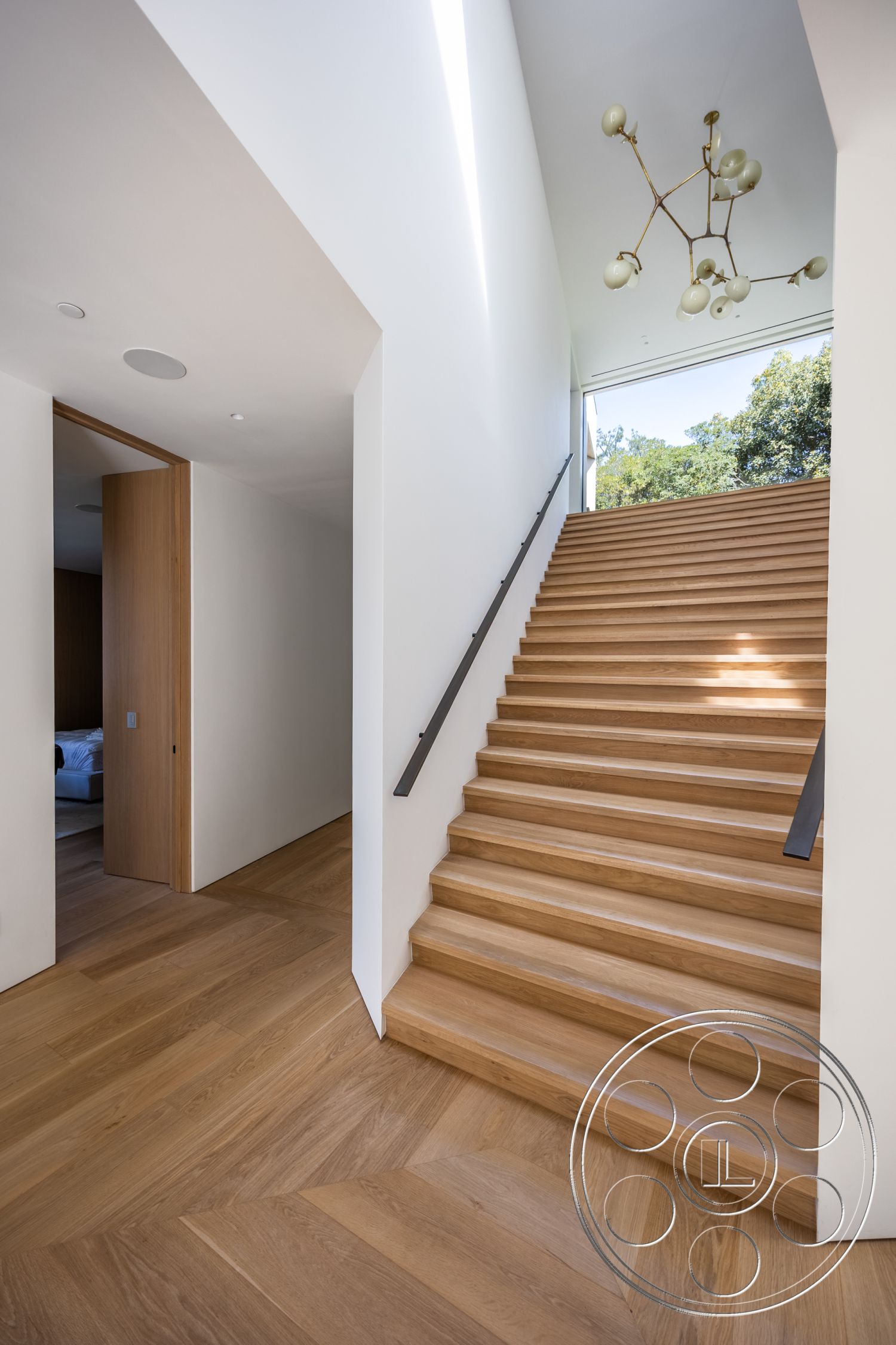Modern 511 - neutral color palette, exposed beam ceiling, floor-to-ceiling windows, modern pendant light fixture, clean architectural lines, functional entryway design, interior wooden staircase, hardwood flooring with herringbone pattern, minimalist white walls, open entrance foyer, contemporary door design, sleek metal handrail, spacious landing area, natural light accentuating space